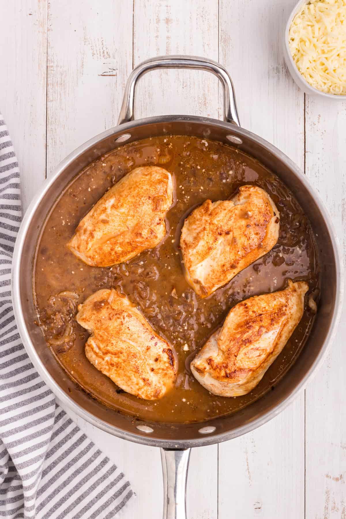 Overhead picture of cooked chicken and french onion sauce in a pan.