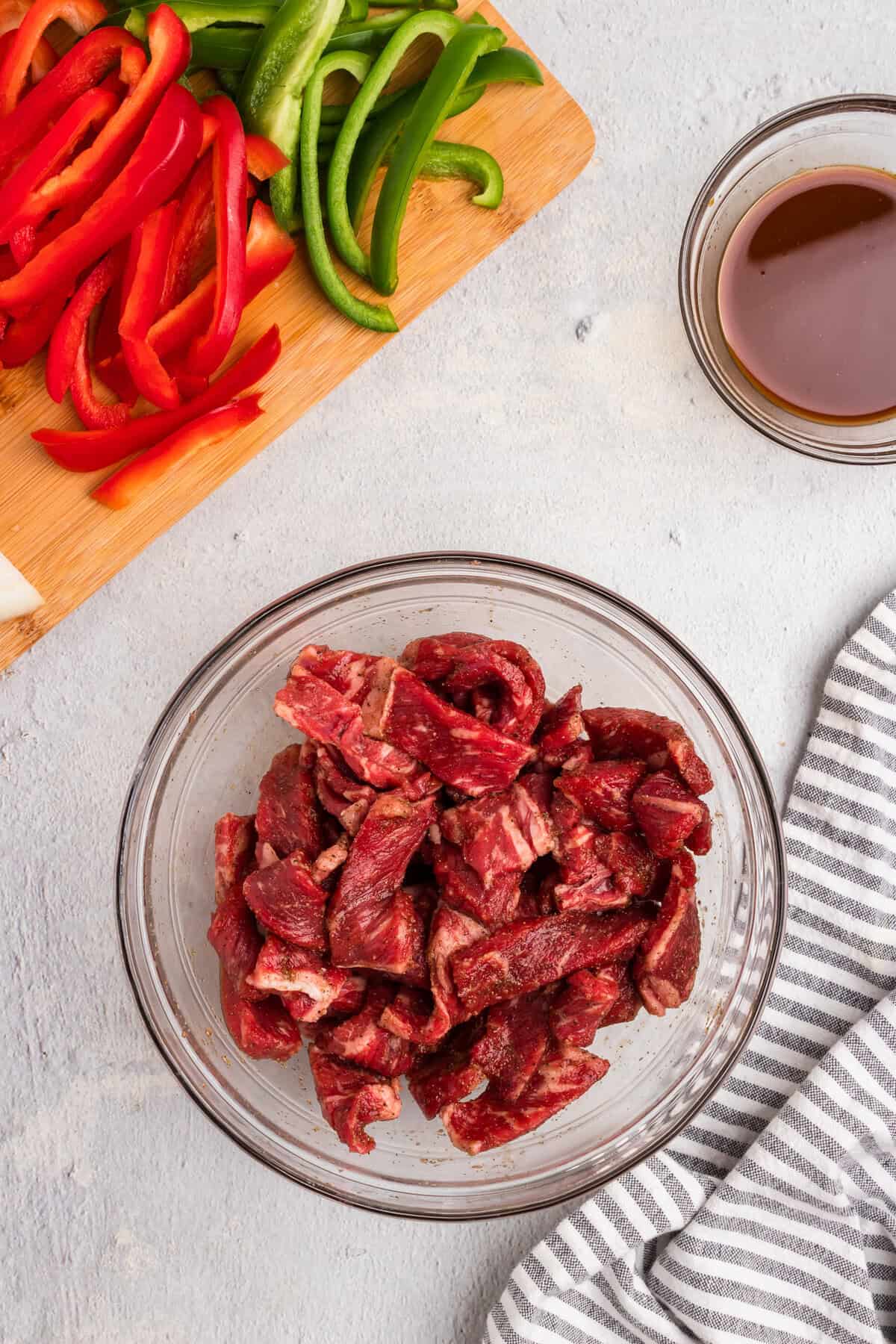 Overhead picture of raw steak and veggies in a bowl and on a cutting board.