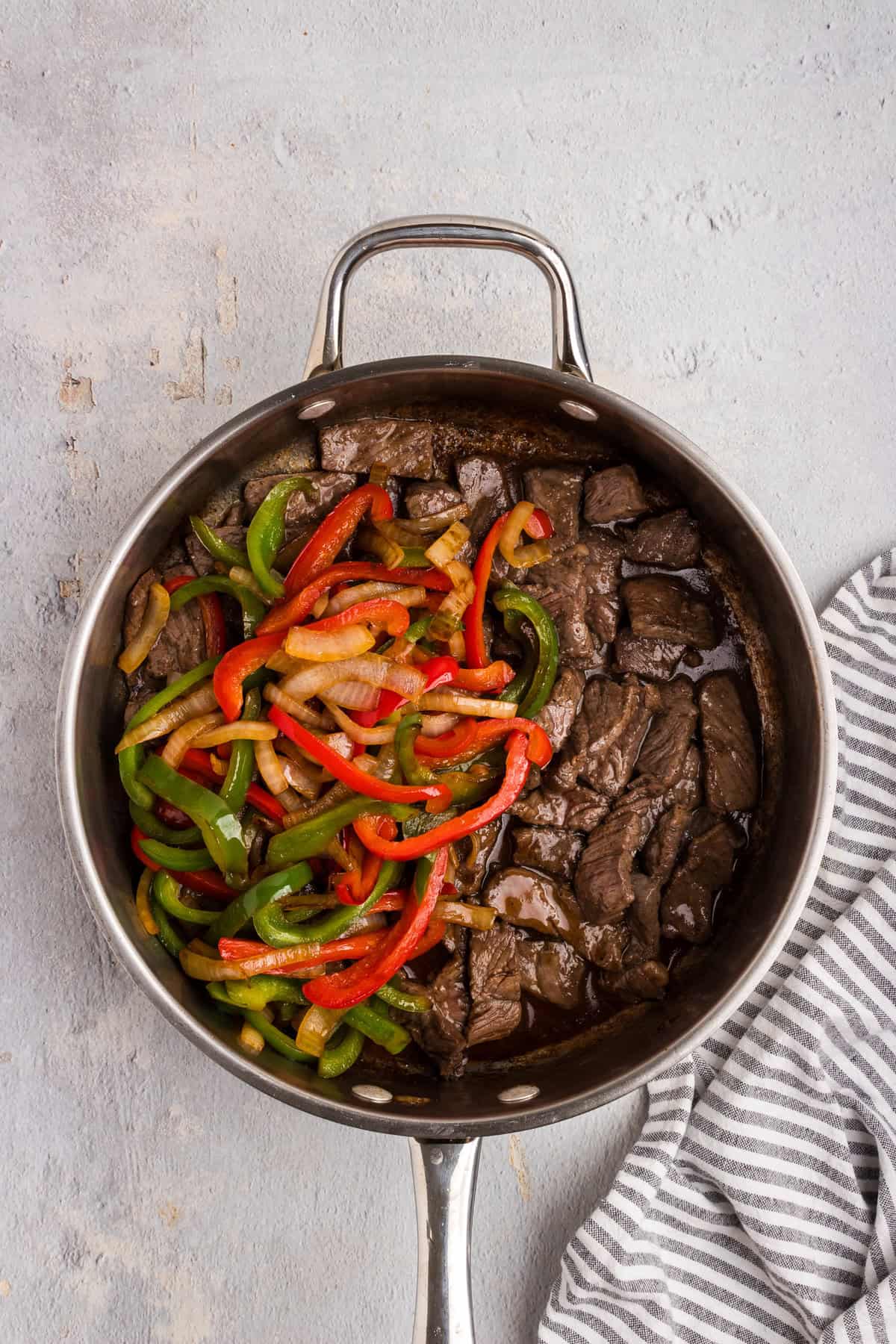Overhead picture of cooked peppers and steak unmixed in a pan.