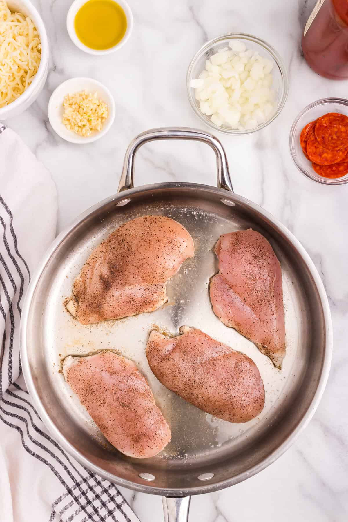 Overhead picture of uncooked chicken breast in a frying pan.