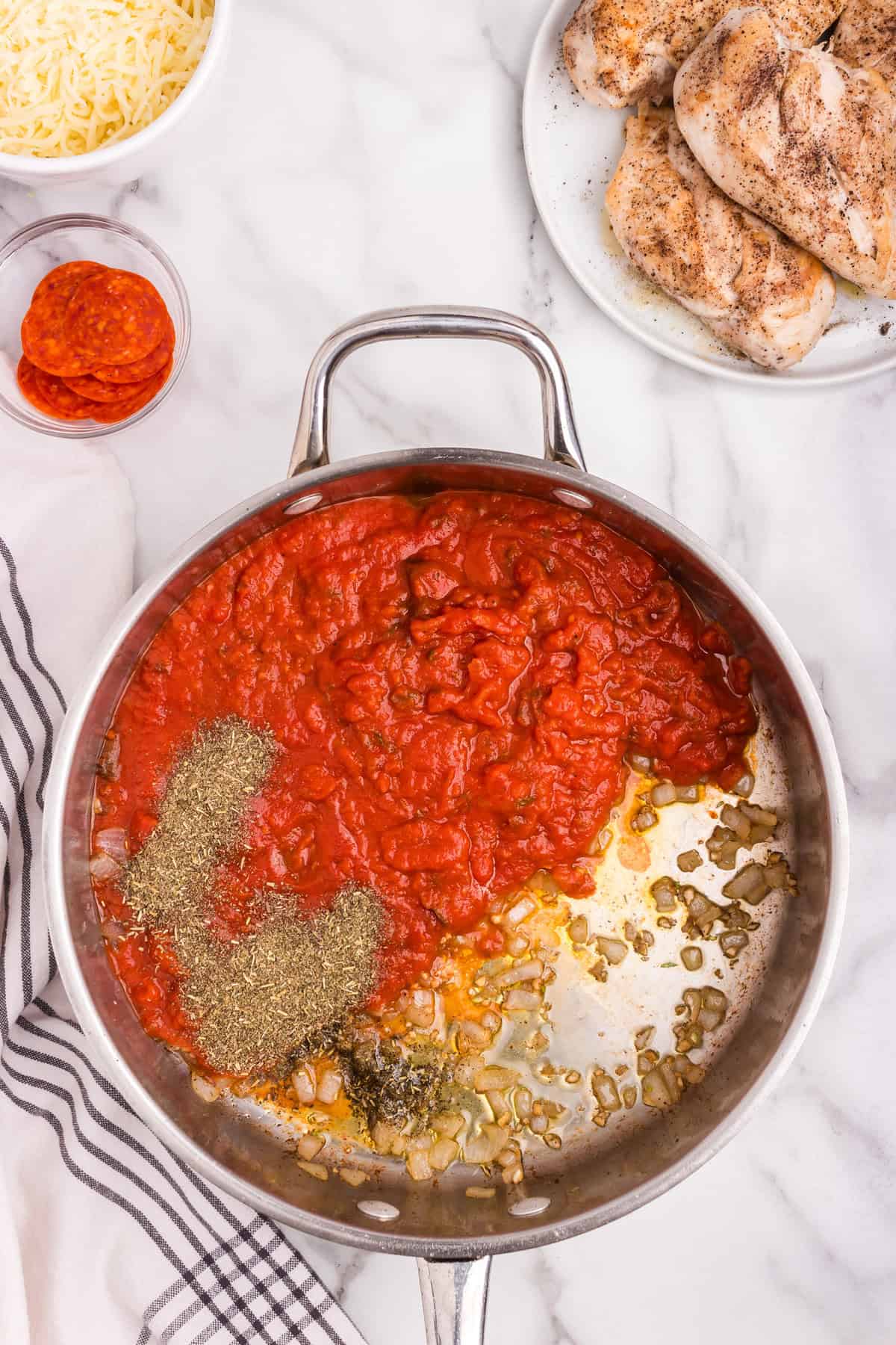 Overhead picture of pizza sauce and seasonings in a pan not mixed.