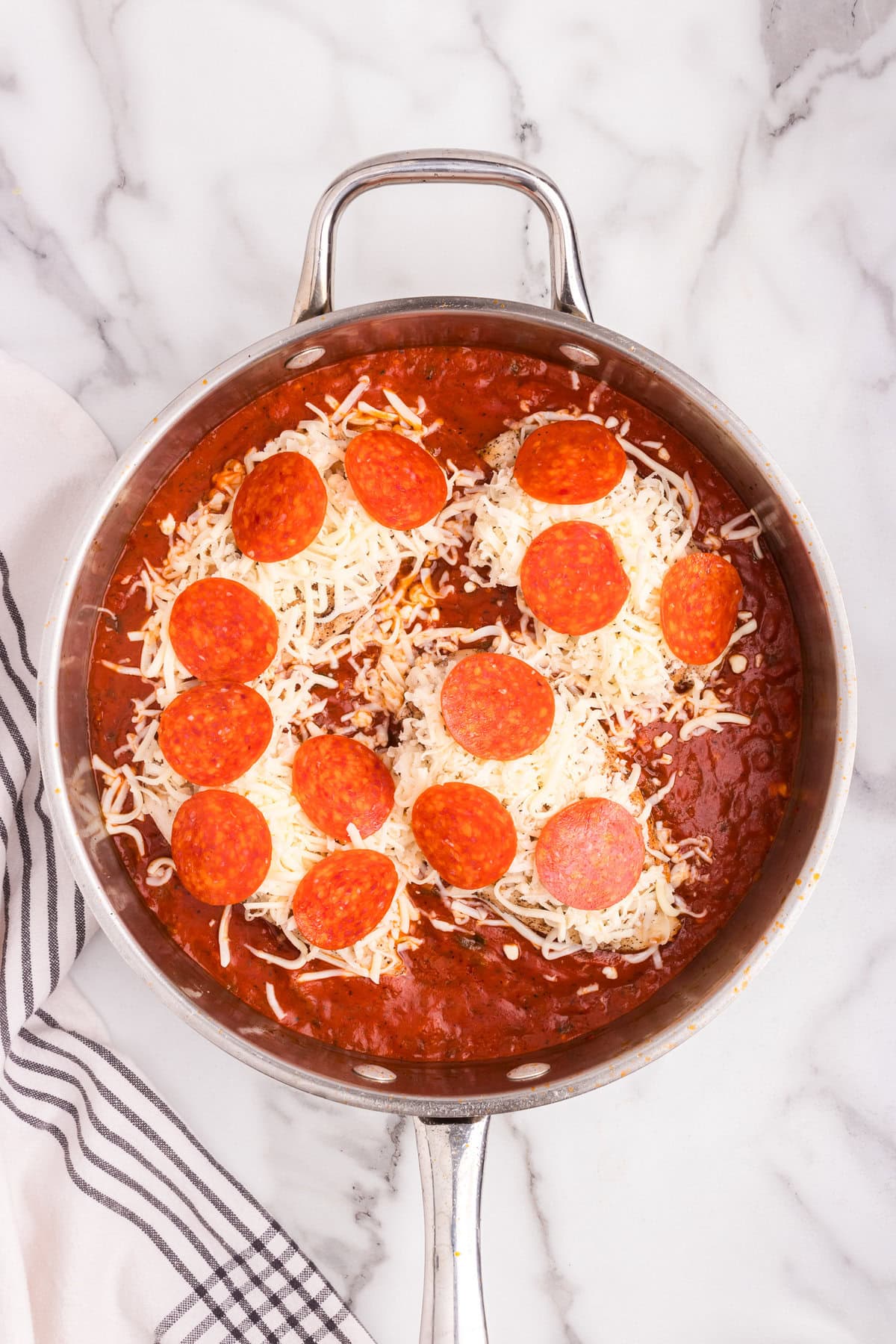 Overhead picture of pizza chicken in a pan with mozzarella cheese unmelted on top.