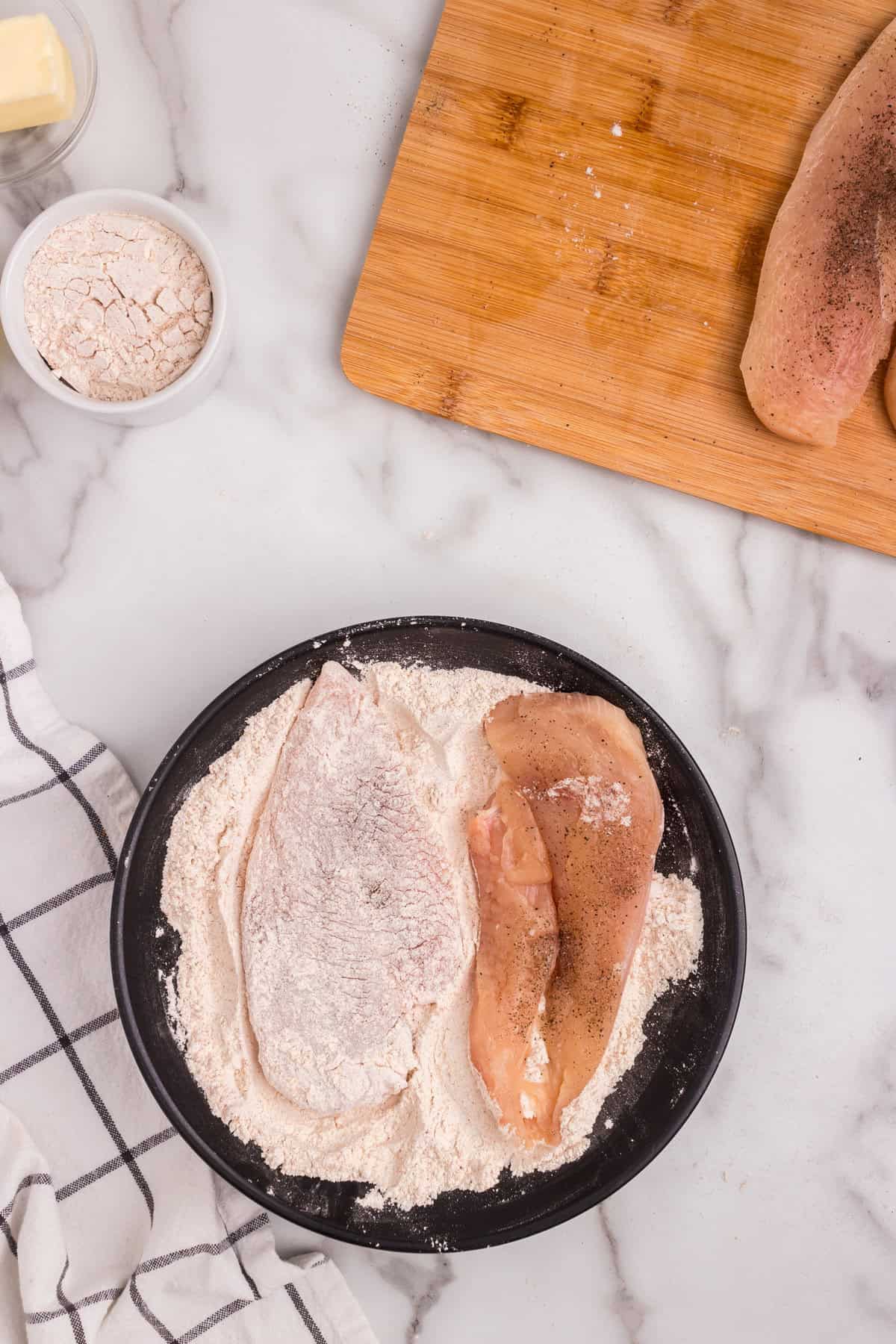 Overhead picture of raw chicken breast breaded in flour mixture.