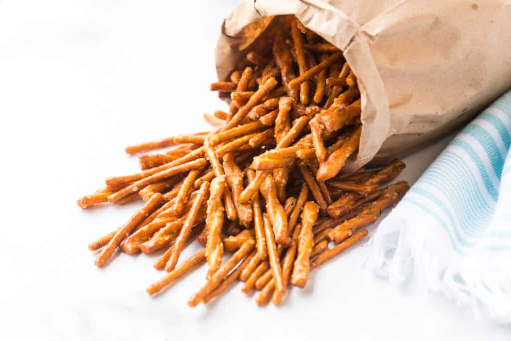 Paper bag with ranch seasoned pretzels falling out of it on white background