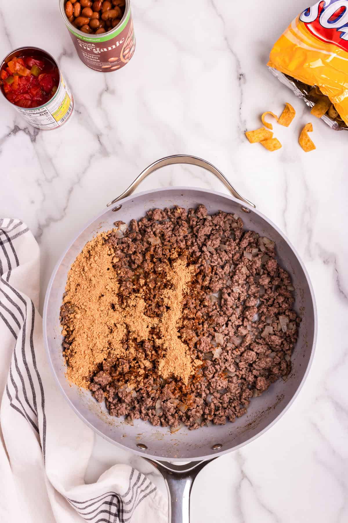 Overhead picture of cooked ground beef and taco seasoning in a pan unmixed.