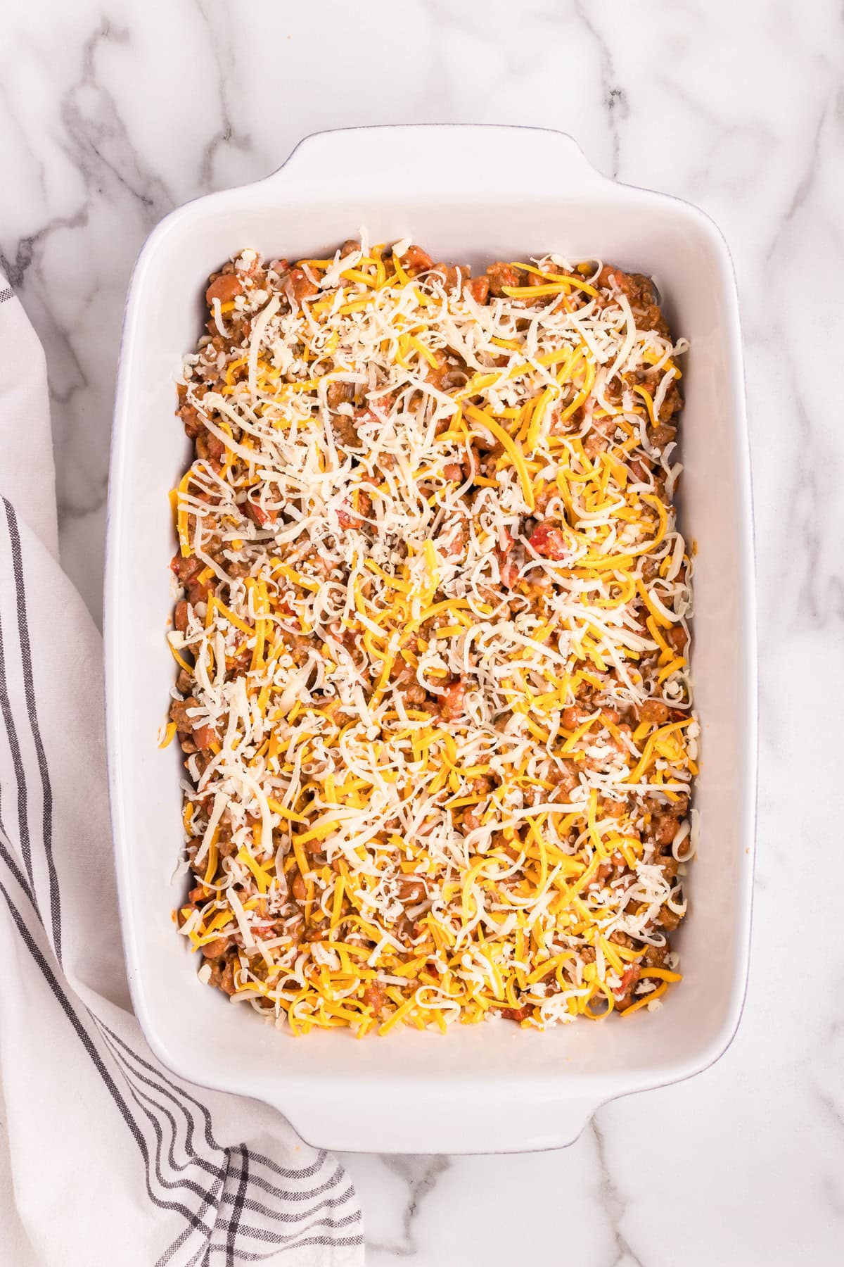 Overhead picture of uncooked walking taco casserole in a white baking dish.