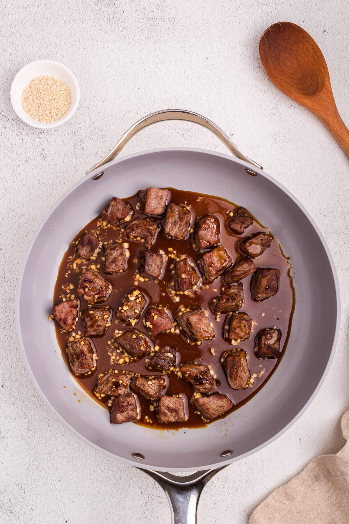 The beef cubes remain in the skillet while the mixed teriyaki sauce is added, coating the beef evenly.