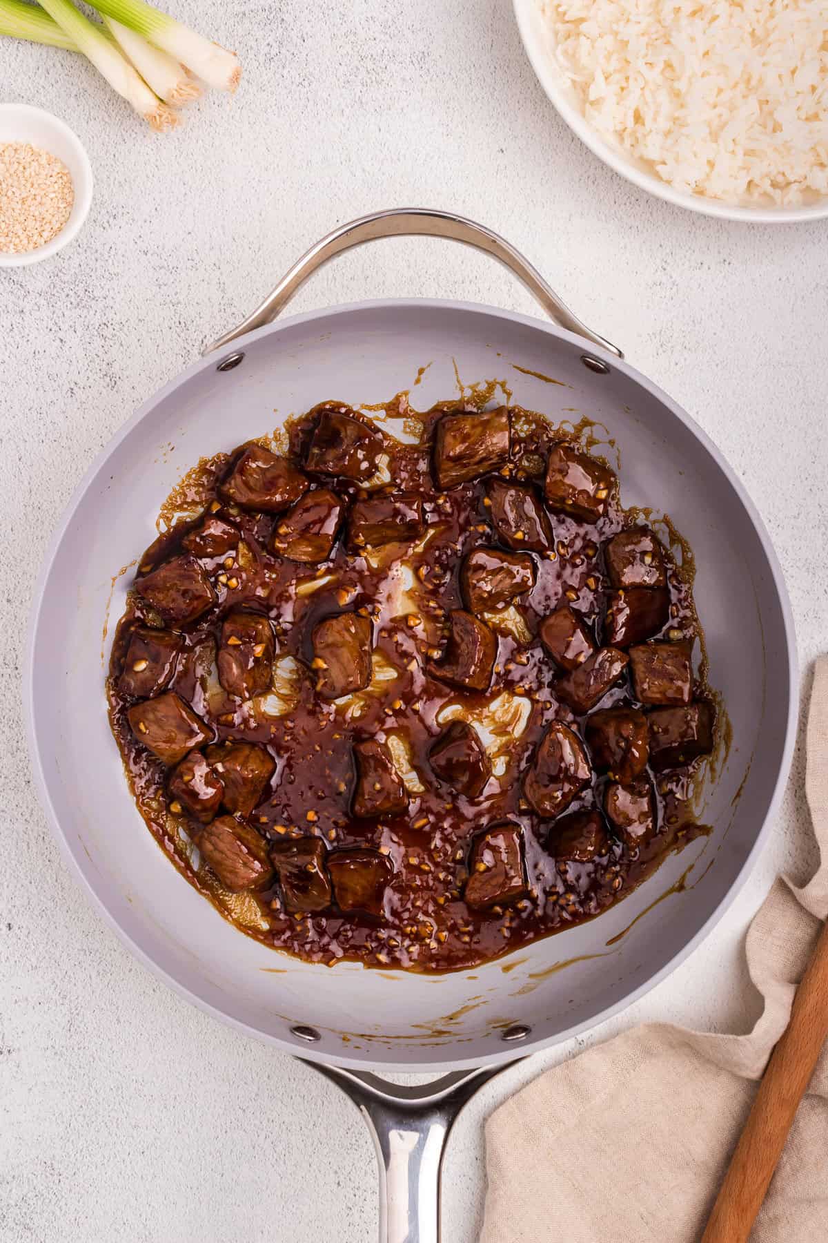 The sauce has thickened and is bubbling, now coating the beef chunks thoroughly for a glossy finish.