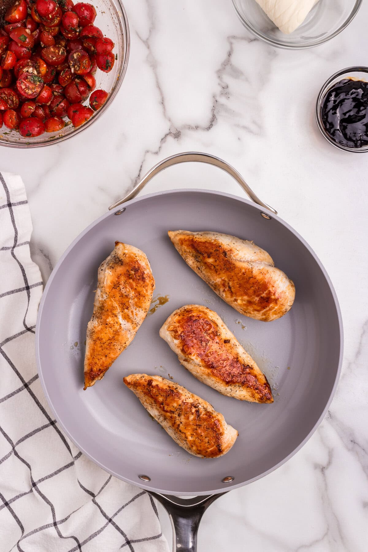 The chicken breasts are seared and golden brown on one side, cooking in the skillet.