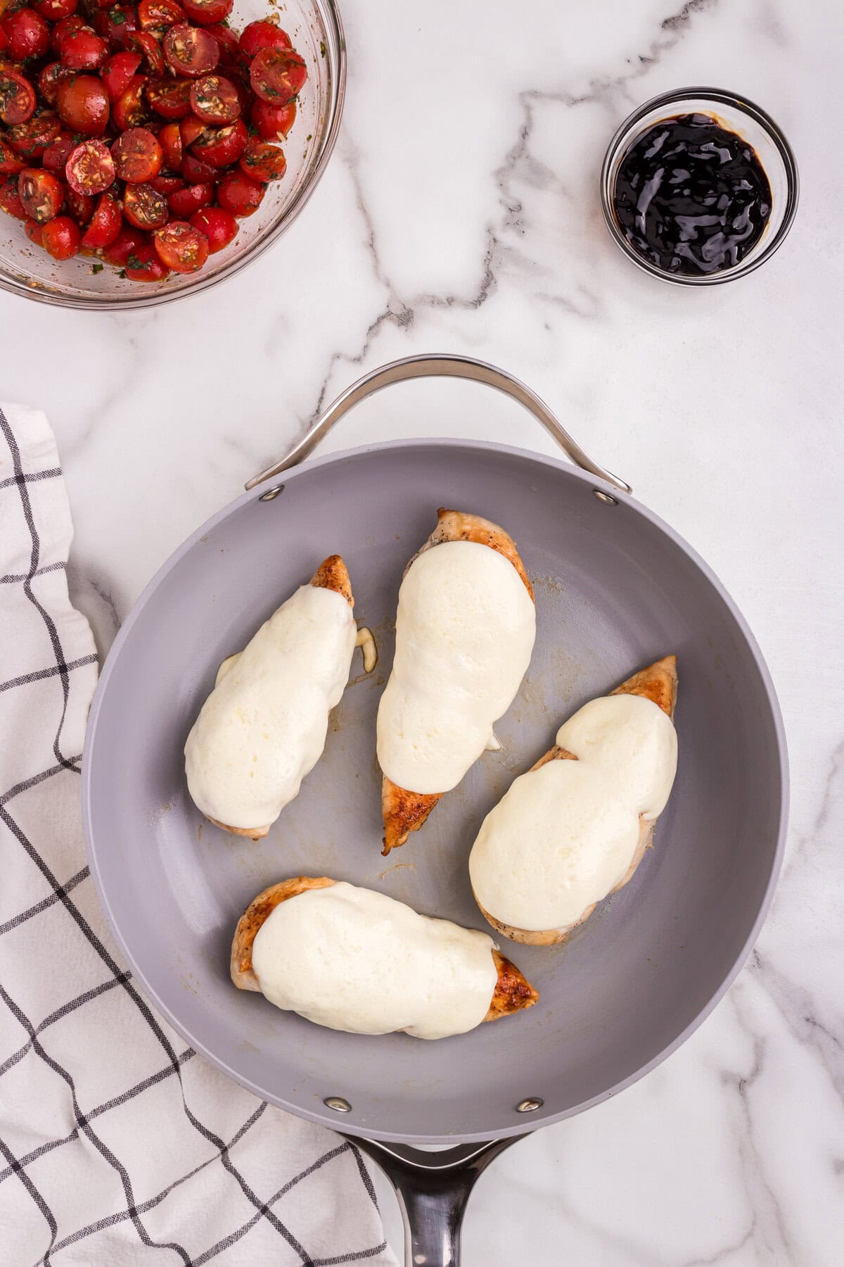 he mozzarella cheese has melted over the chicken breasts, fully covering them.