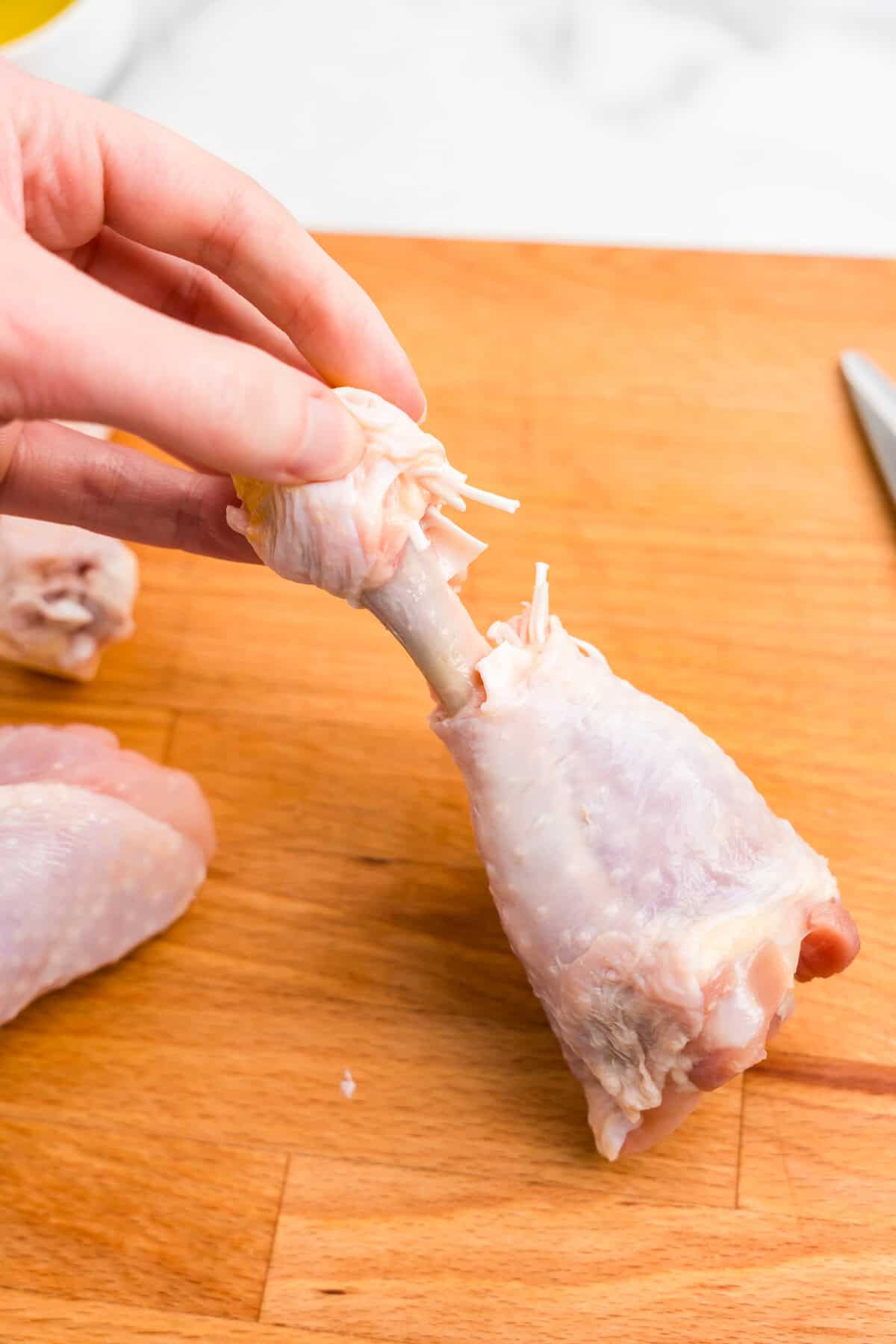 Cutting skin and pulling back it on a chicken drumsticks