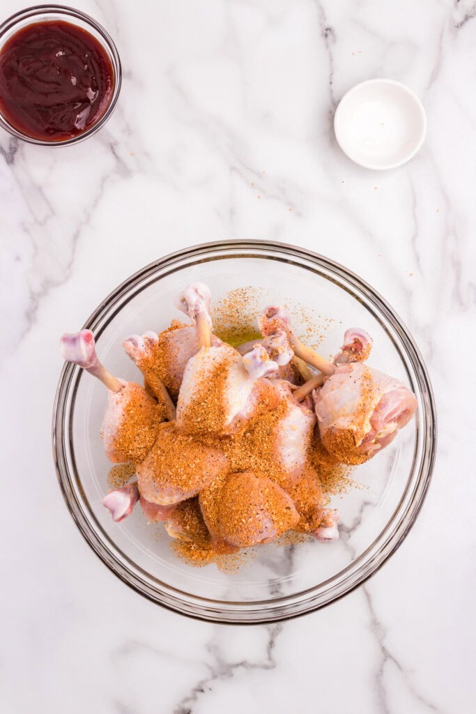 Chicken Lollipops Drumsticks in glass bowl with seasoning