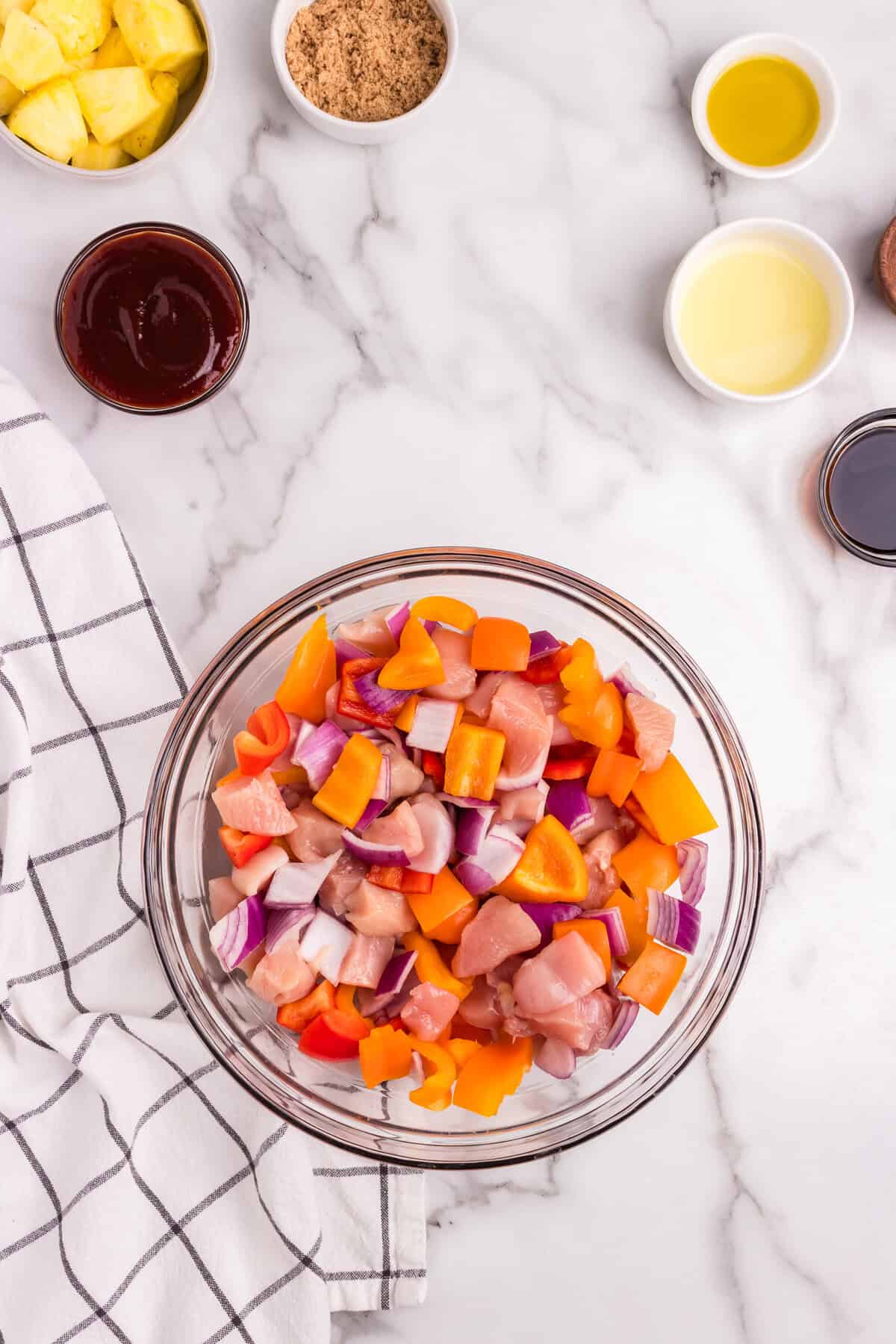 The same glass mixing bowl with the ingredients now evenly mixed together, combining the chicken, bell peppers, and onions.