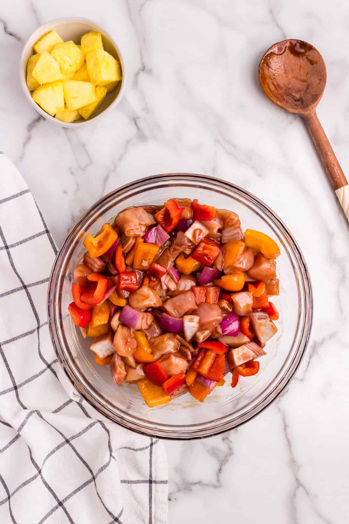 The ingredients in the bowl have been thoroughly coated in the sauce, with the chicken, peppers, and onions glistening in the marinade.