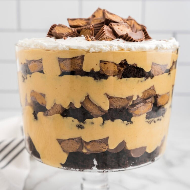 A fully assembled Reese’s Peanut Butter Trifle with layers of brownies, peanut butter filling, and Reese’s cups, topped with whipped cream and more candy.