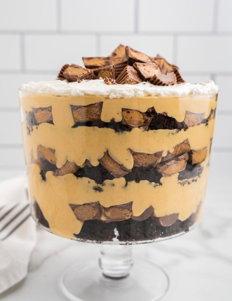 A fully assembled Reese’s Peanut Butter Trifle with layers of brownies, peanut butter filling, and Reese’s cups, topped with whipped cream and more candy.