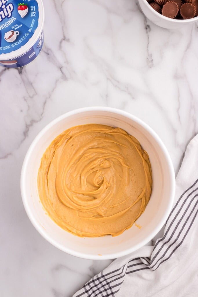 A bowl filled with smooth, creamy peanut butter pudding on a marble countertop, ready to be used in a dessert recipe.