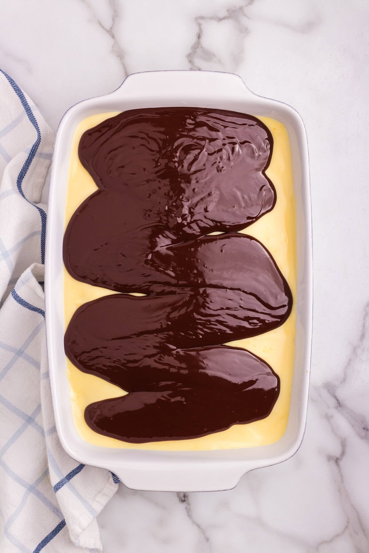 The poked cake topped with thick layers of vanilla pudding and do