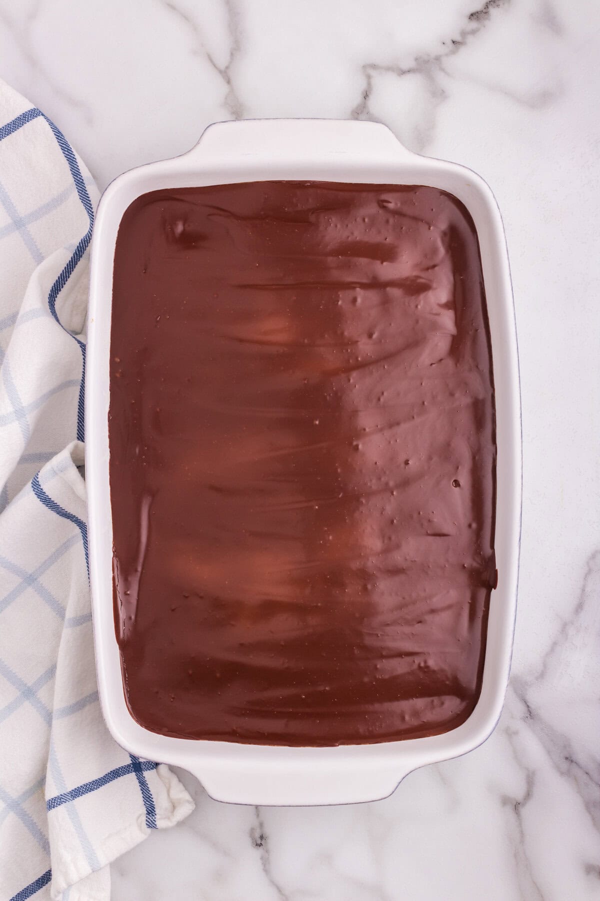 The cake now fully covered with a smooth, glossy layer of chocolate ganache.