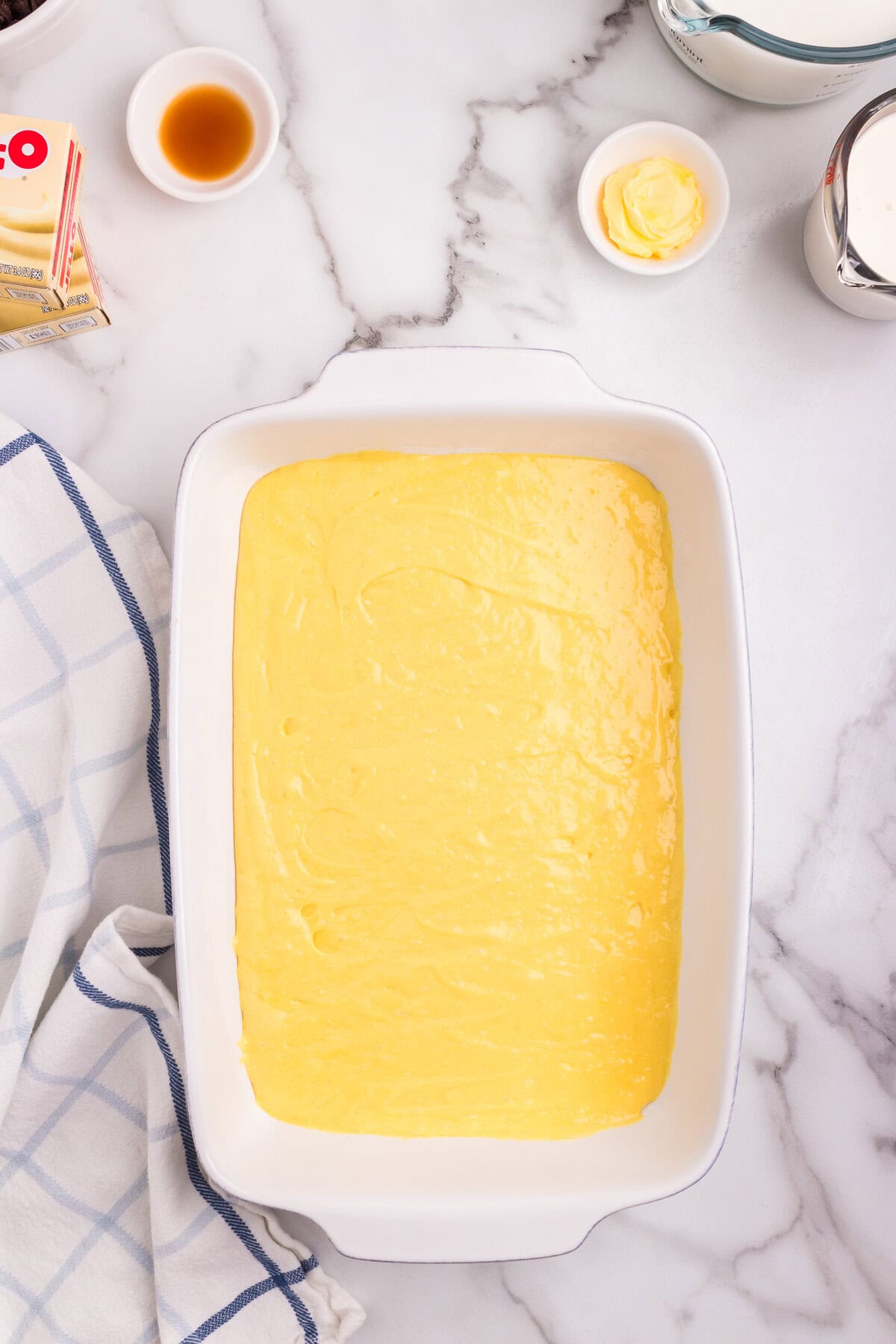 The smooth yellow cake batter spread evenly in a white rectangular baking dish, ready to be baked.