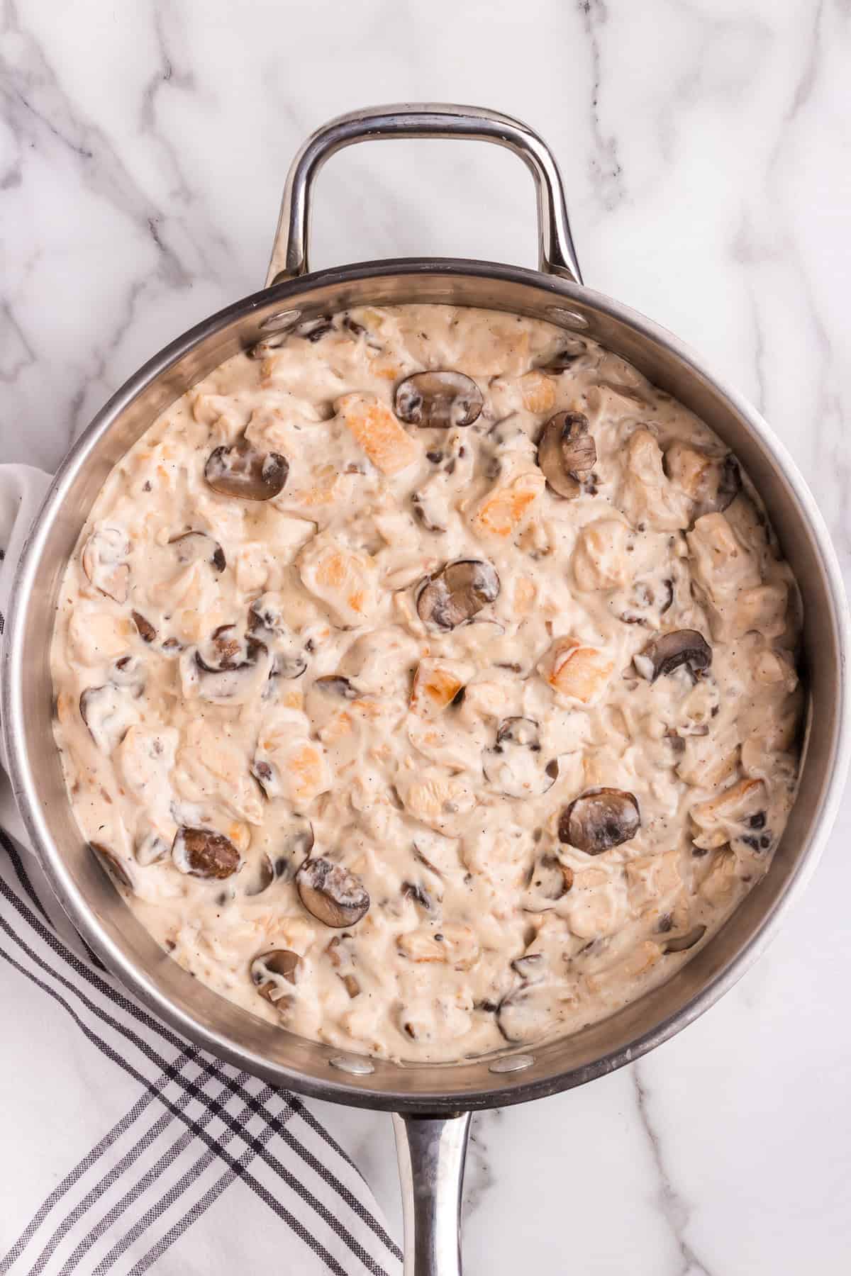 Final mixture of chicken, mushrooms, cream of mushroom soup, and sour cream fully combined and creamy in the skillet.