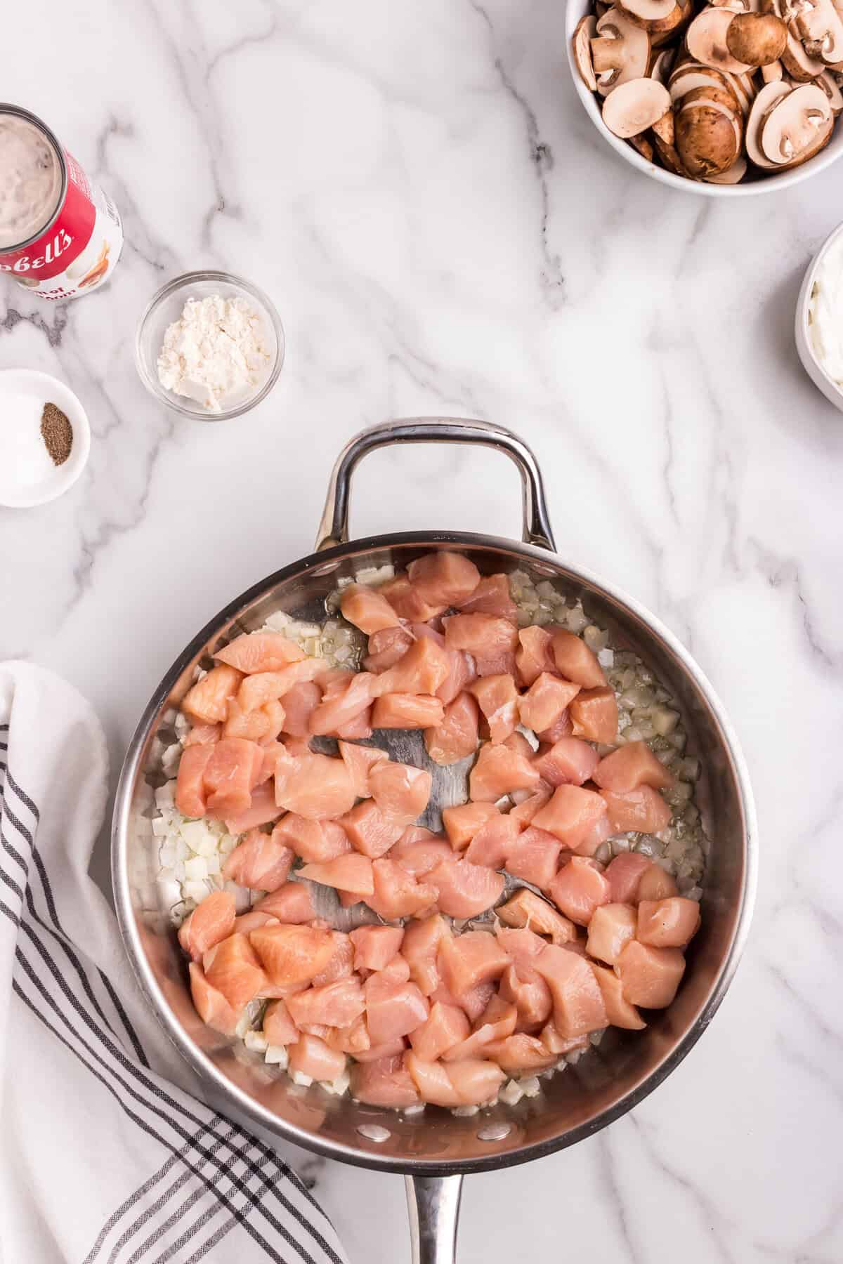 Raw diced chicken added to the skillet over the sautéed onions, ready to be cooked
