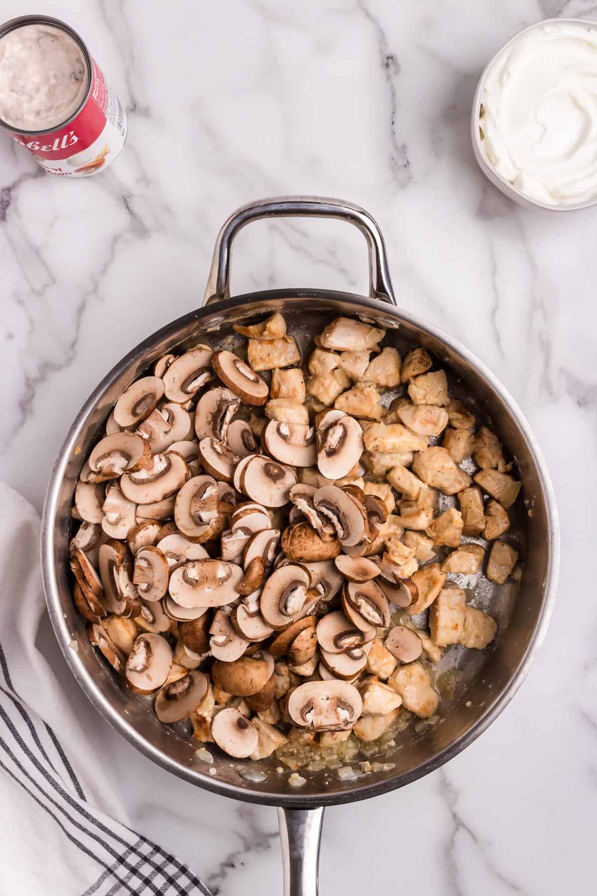 Sliced mushrooms added to one side of the skillet with the cooked chicken on the other side.
