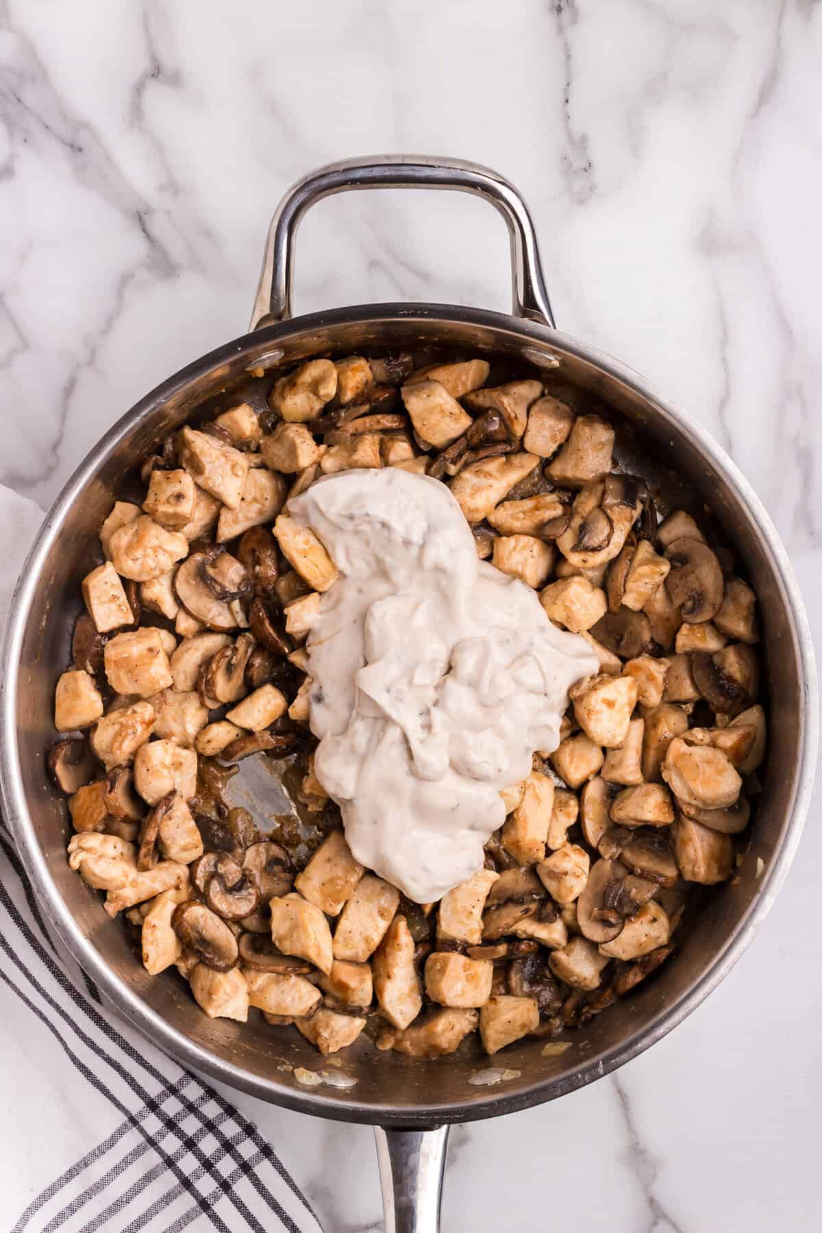 Cream of mushroom soup added to the chicken and mushroom mixture in the skillet.