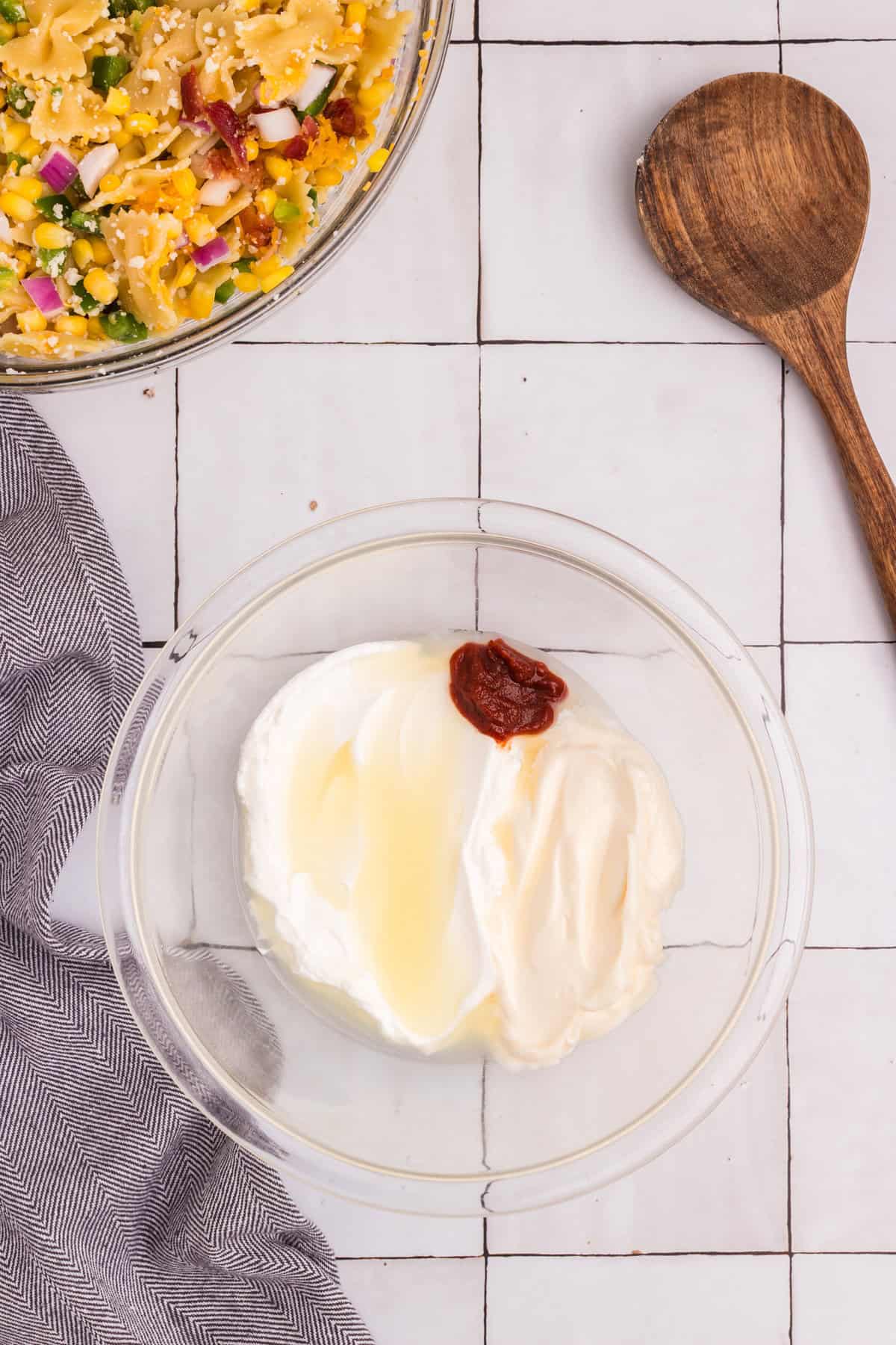 A glass bowl with mayonnaise, sour cream, lime juice, and chipotle sauce, ready to be mixed into a creamy dressing.