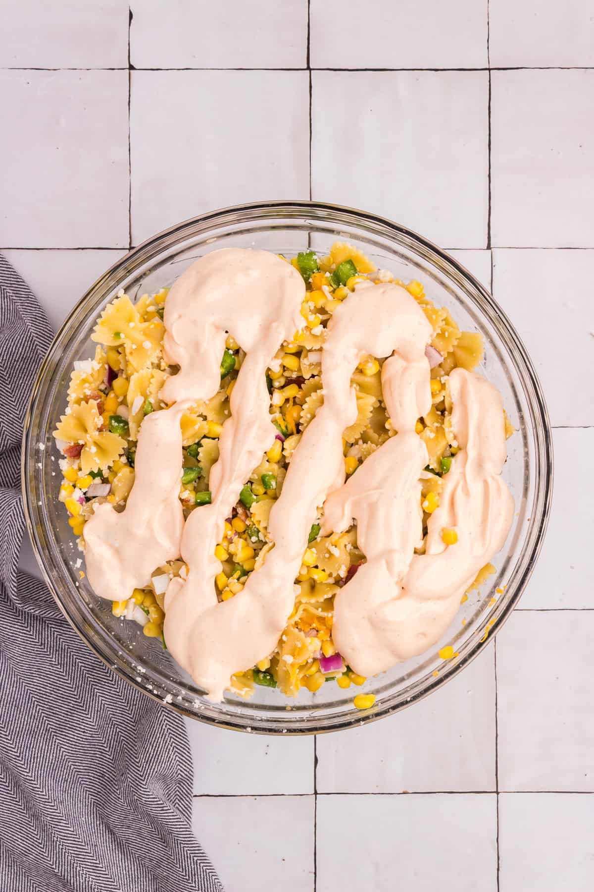 Thick chipotle dressing spooned over the mixed pasta and vegetables, not yet stirred in.