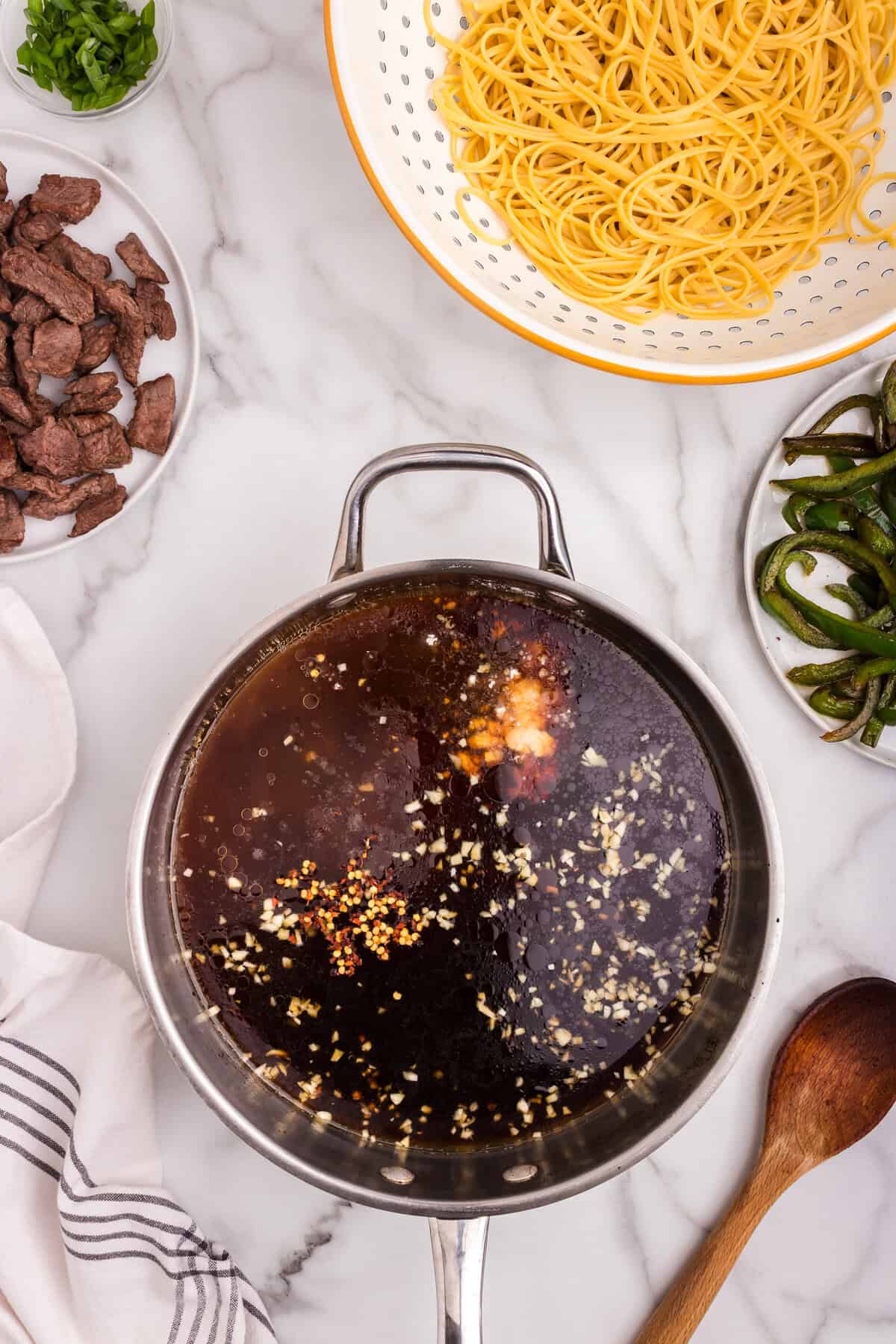 Sauce ingredients, including garlic, soy sauce, sesame oil, and red pepper flakes, added to the skillet.