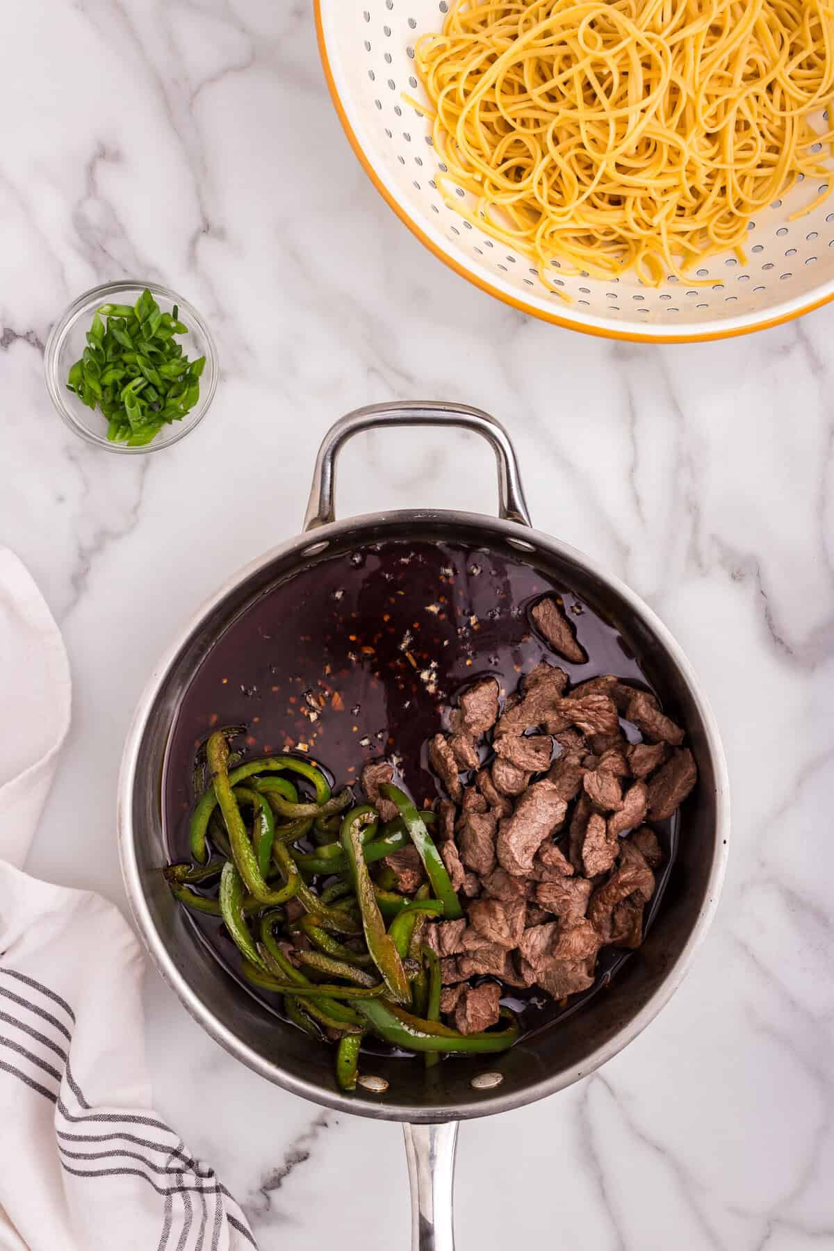 Cooked beef and peppers returned to the skillet with the sauce for mixing.