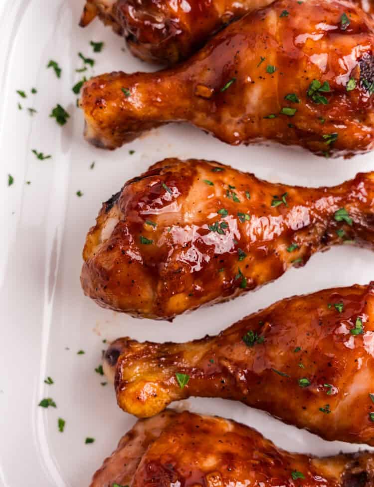 Baked BBQ Chicken Legs on parchment paper with parsley garnish on top