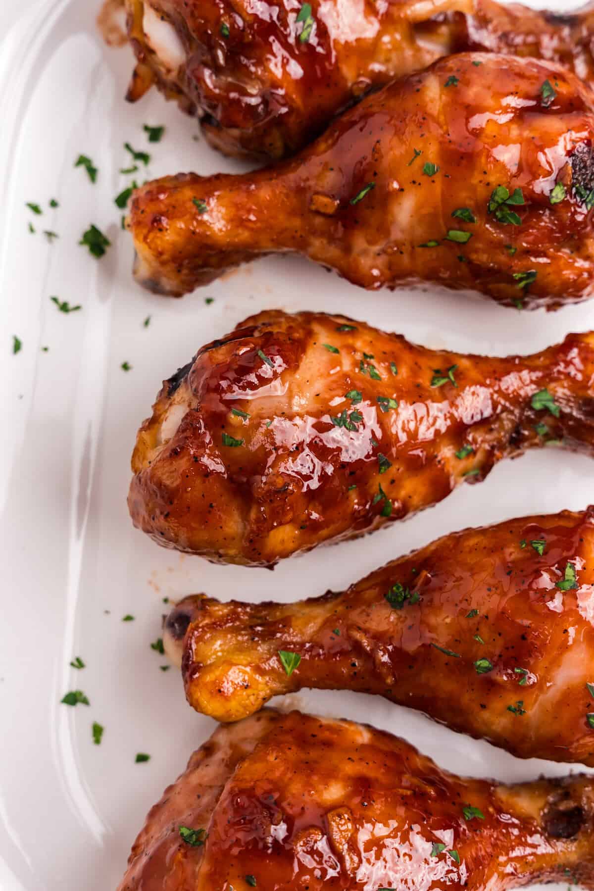 Baked BBQ Chicken Legs on parchment paper with parsley garnish on top