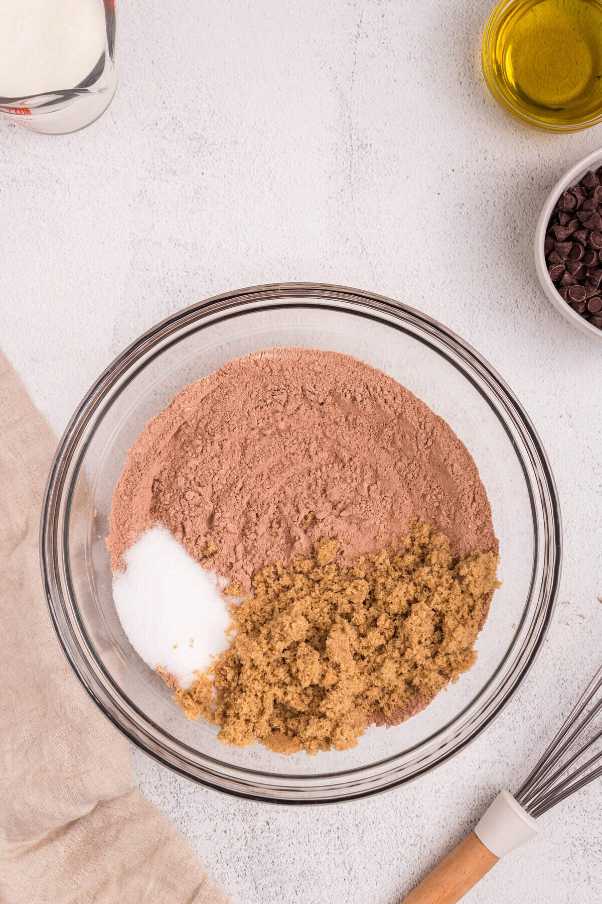 The same bowl of mixed dry ingredients, now with white sugar and brown sugar added on top.