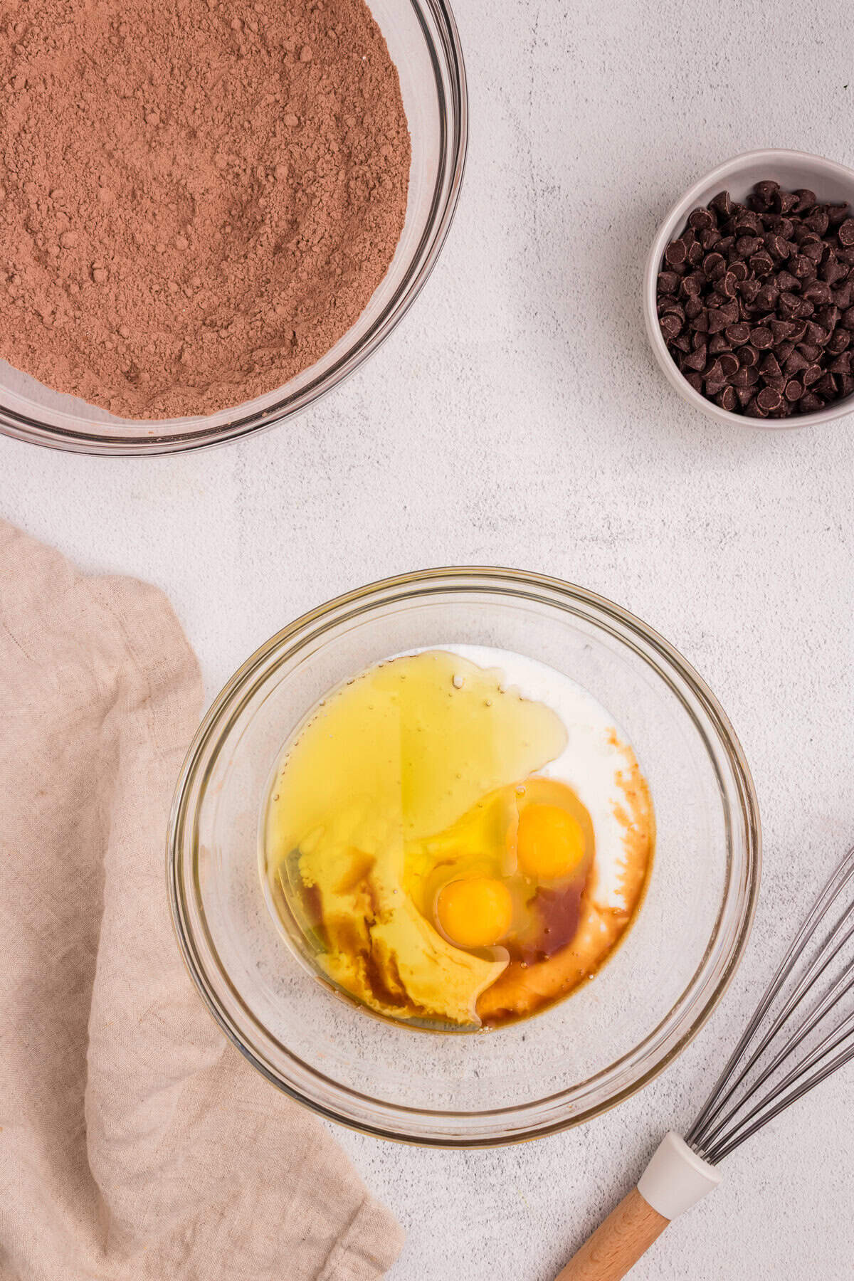 A separate bowl showing the wet ingredients: two eggs, vanilla extract, and milk, ready to be mixed.