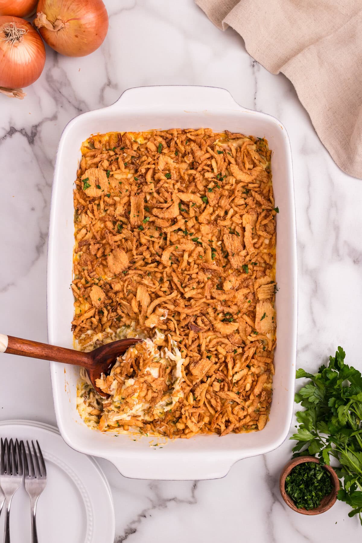 A wooden spoon scooping into the crispy-topped casserole, revealing the creamy chicken and green bean filling underneath.