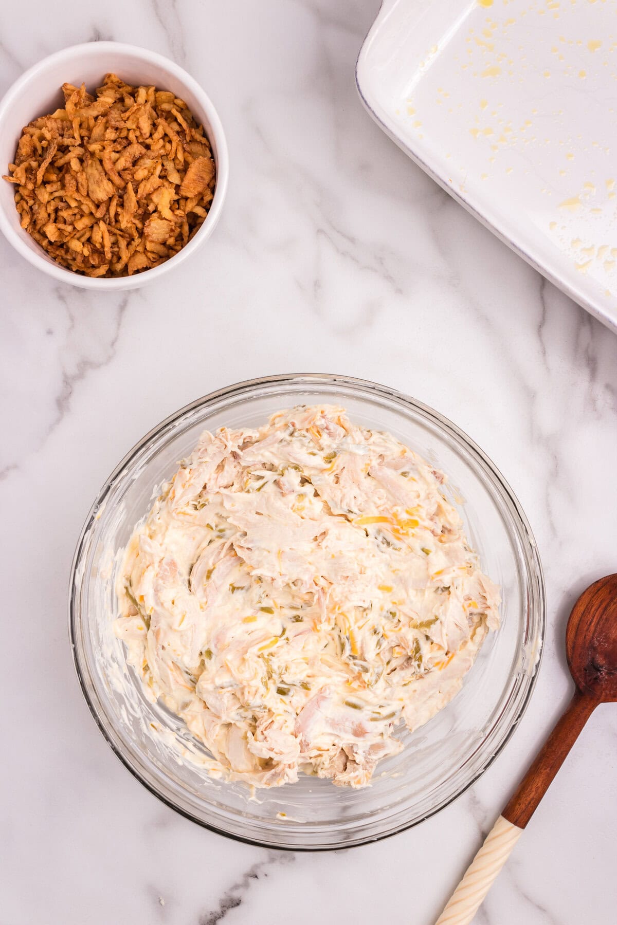 All ingredients, including shredded chicken, now thoroughly combined into a creamy casserole filling in the glass bowl.