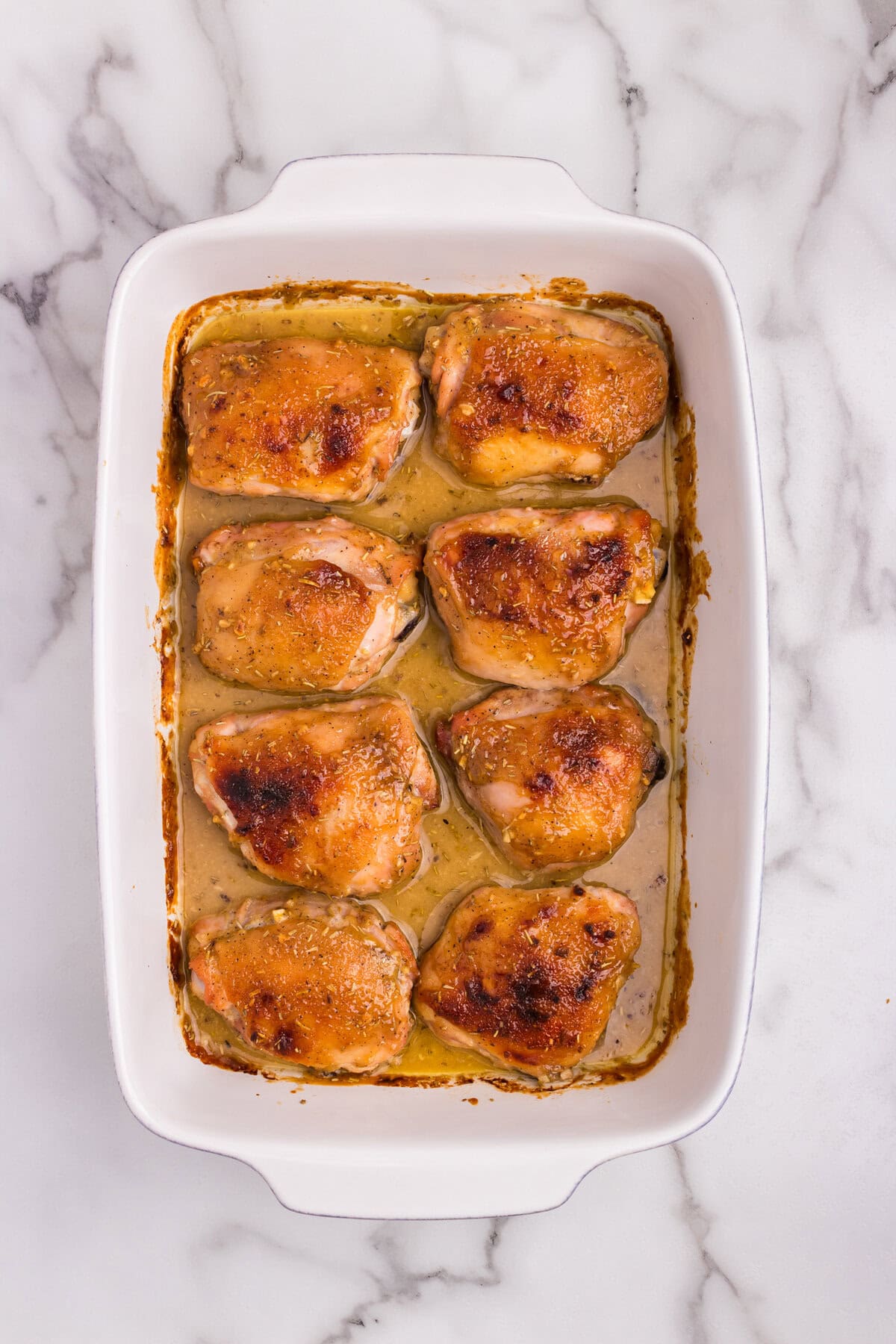 All chicken thighs baked to golden brown with caramelized edges in a white baking dish.