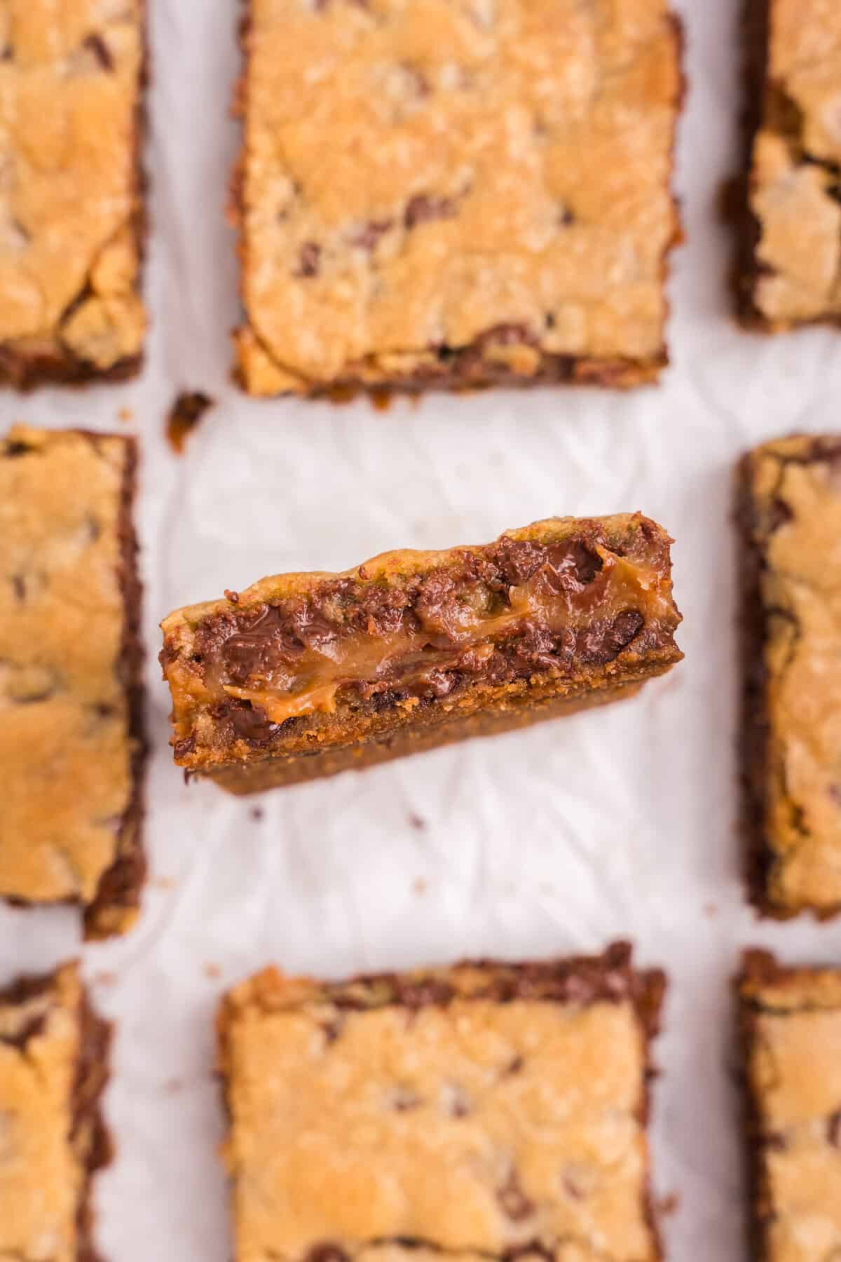 A close-up of one bar held vertically, showing a gooey, melted center of caramel and chocolate between two layers of golden cookie.