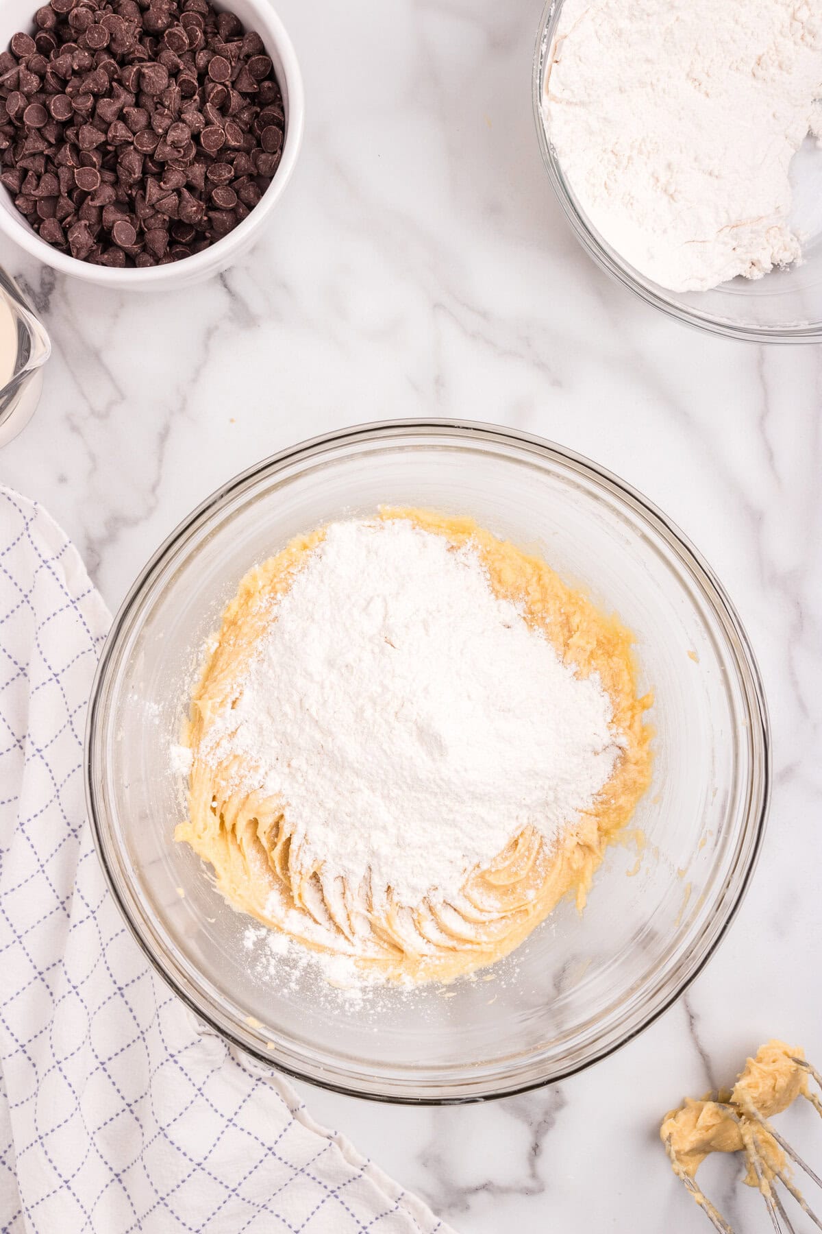 The first addition of flour is added on top of the wet mixture in the bowl.