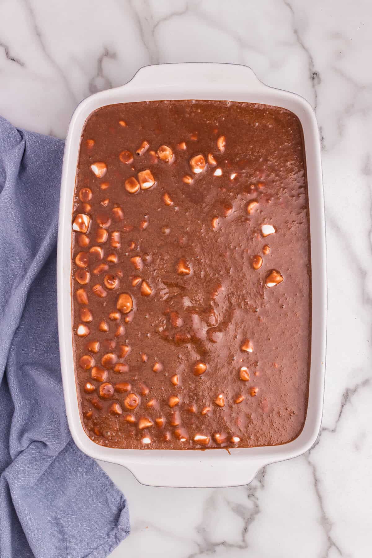 Glaze poured over marshmallows on top of the cake, starting to melt them into the warm topping.