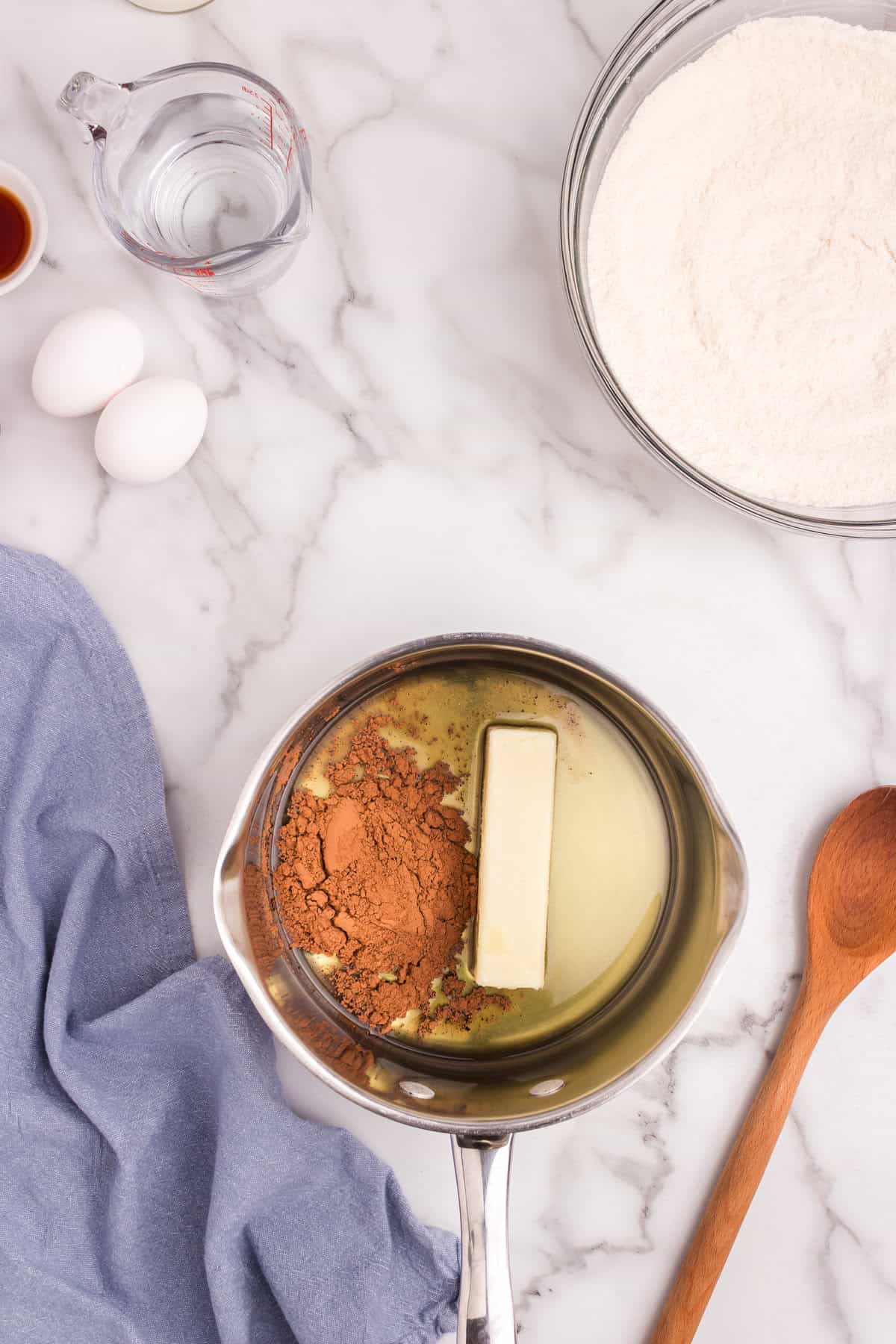 Cocoa powder, butter, and oil added to a saucepan, ready to be melted and combined.