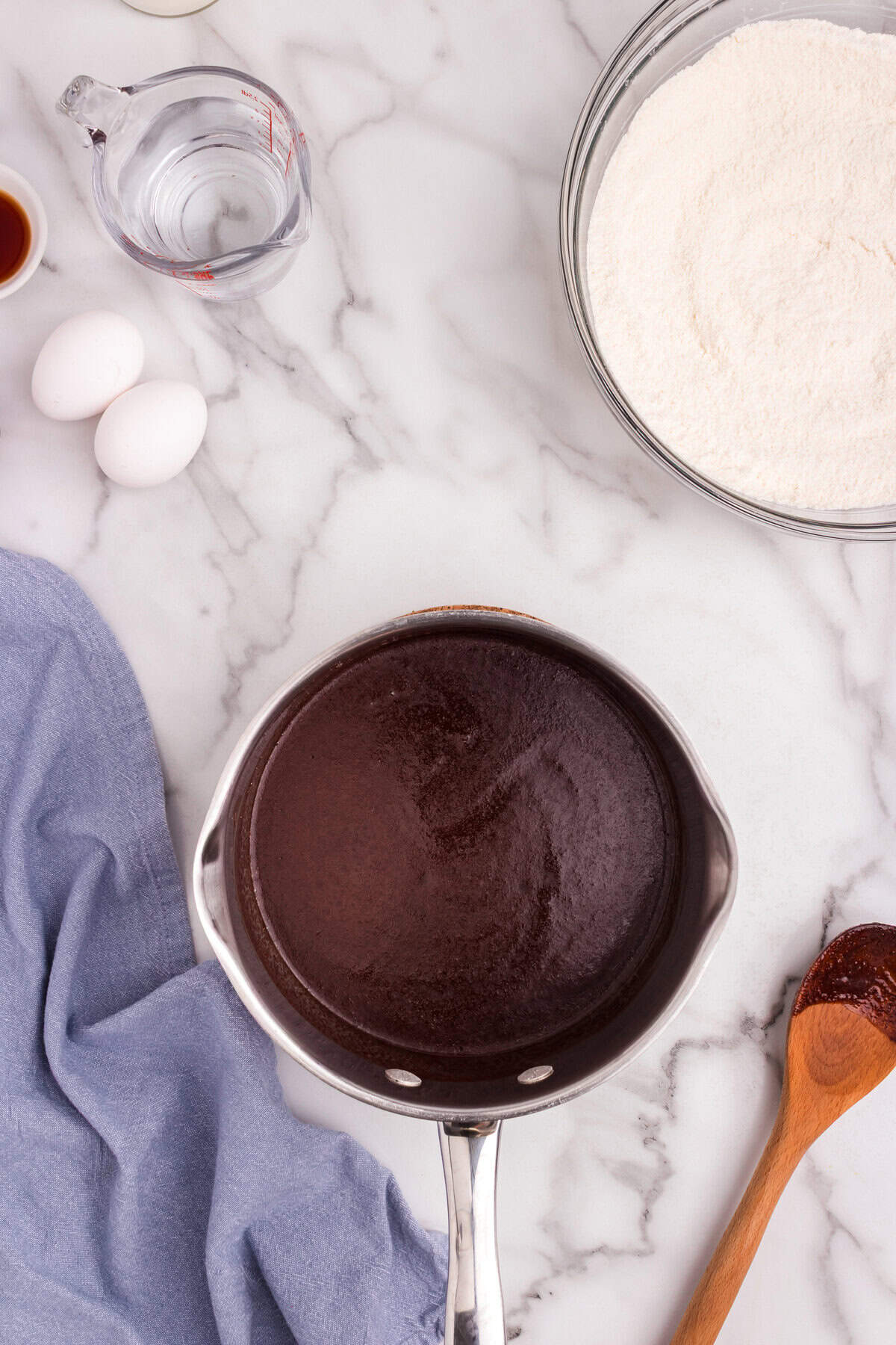 Melted mixture of cocoa powder, butter, and oil in the saucepan, fully blended into a smooth chocolate liquid.