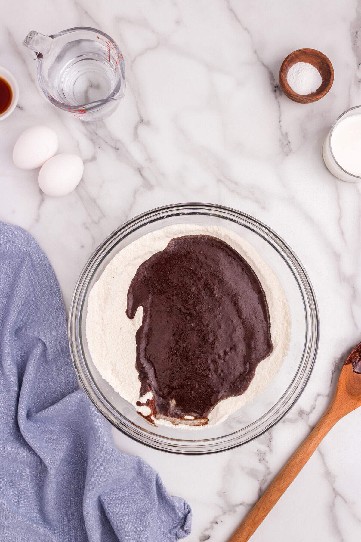 The warm chocolate mixture being poured into the bowl with the flour and sugar mixture.