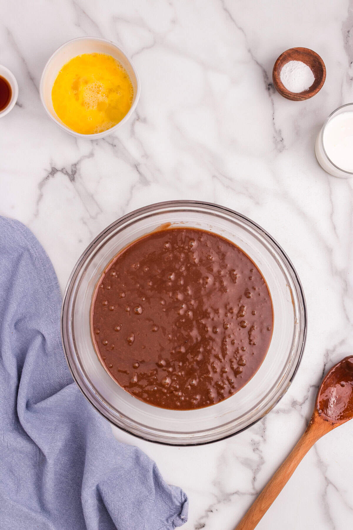 The chocolate mixture and dry ingredients stirred together in a large glass bowl, creating a thick batter.