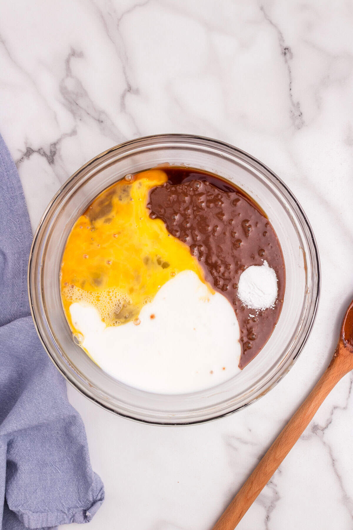Additional ingredients—beaten eggs, milk, baking soda, and vanilla—being added to the chocolate batter in the bowl.