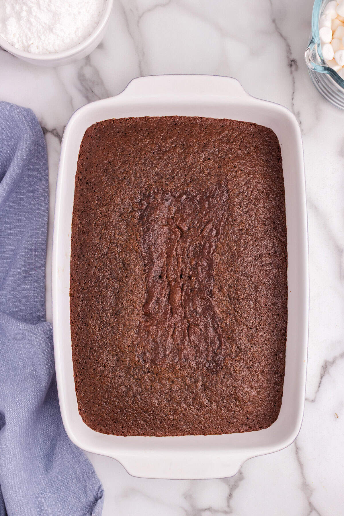 Fully baked chocolate cake in the same white baking dish, with a slightly cracked surface and a rich, dark brown color.