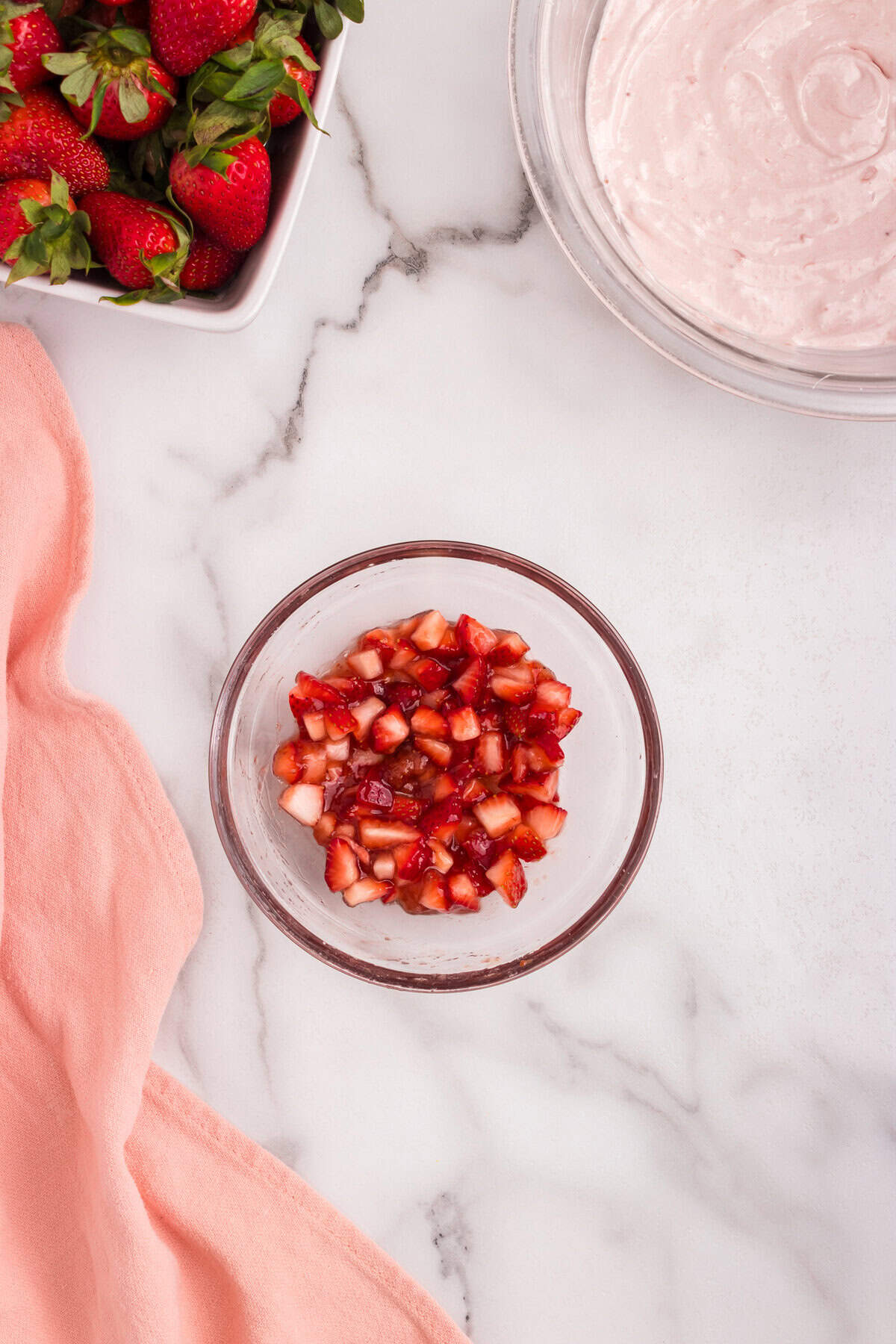Chopped strawberries mixed with strawberry preserves in a small glass bowl, creating a glossy and juicy fruit topping.