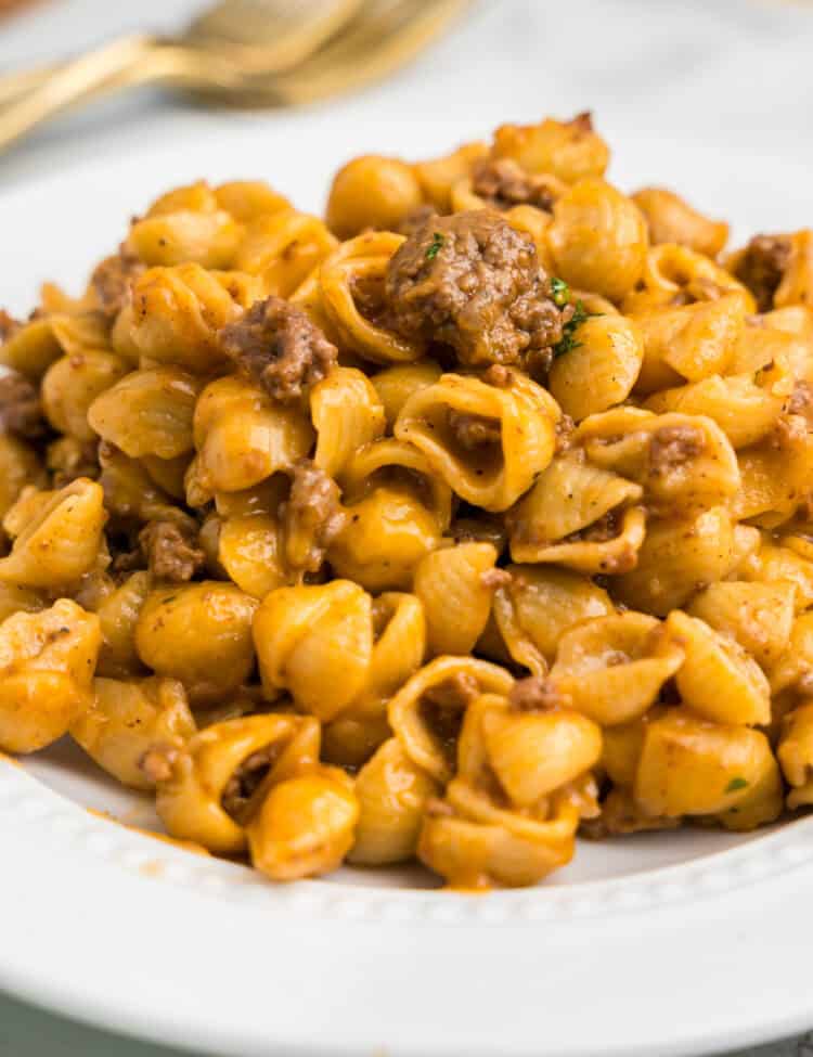 Detailed macro view of cooked cheesy pasta shells with ground beef inside the pot.